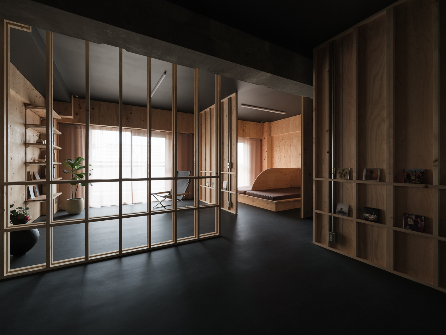 Timber-framed sliding glass partition opening to reveal the sleeping alcove and dark floor