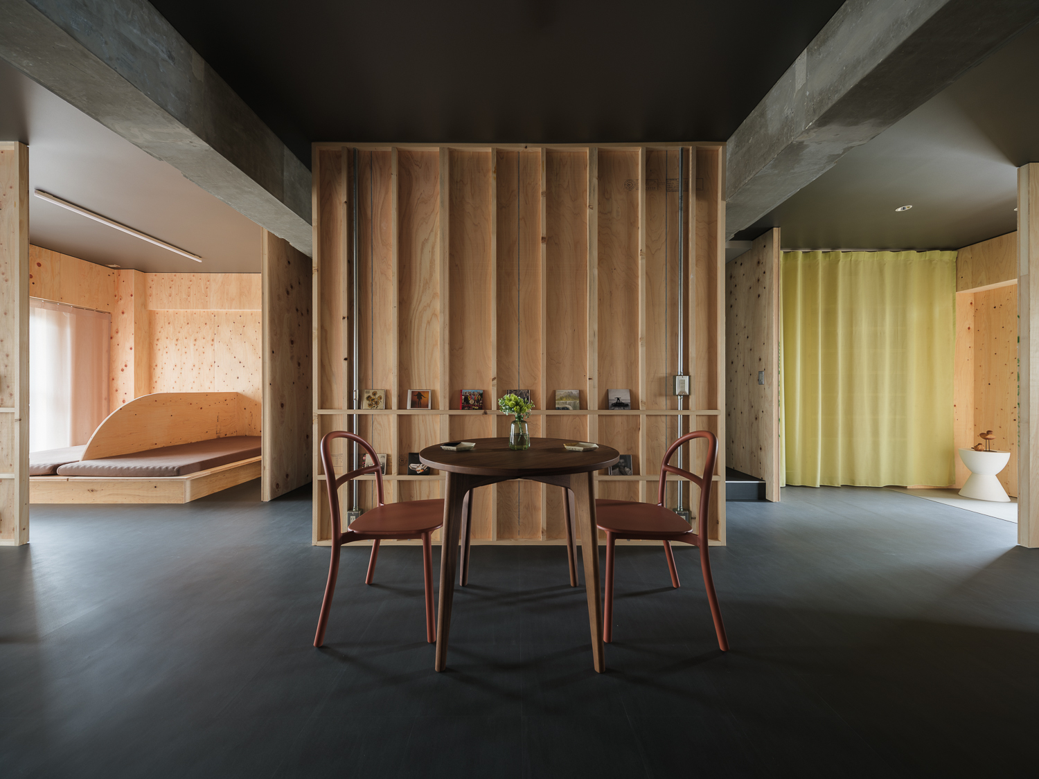 Round dining table with three chairs centered beneath vertical timber slat wall divider