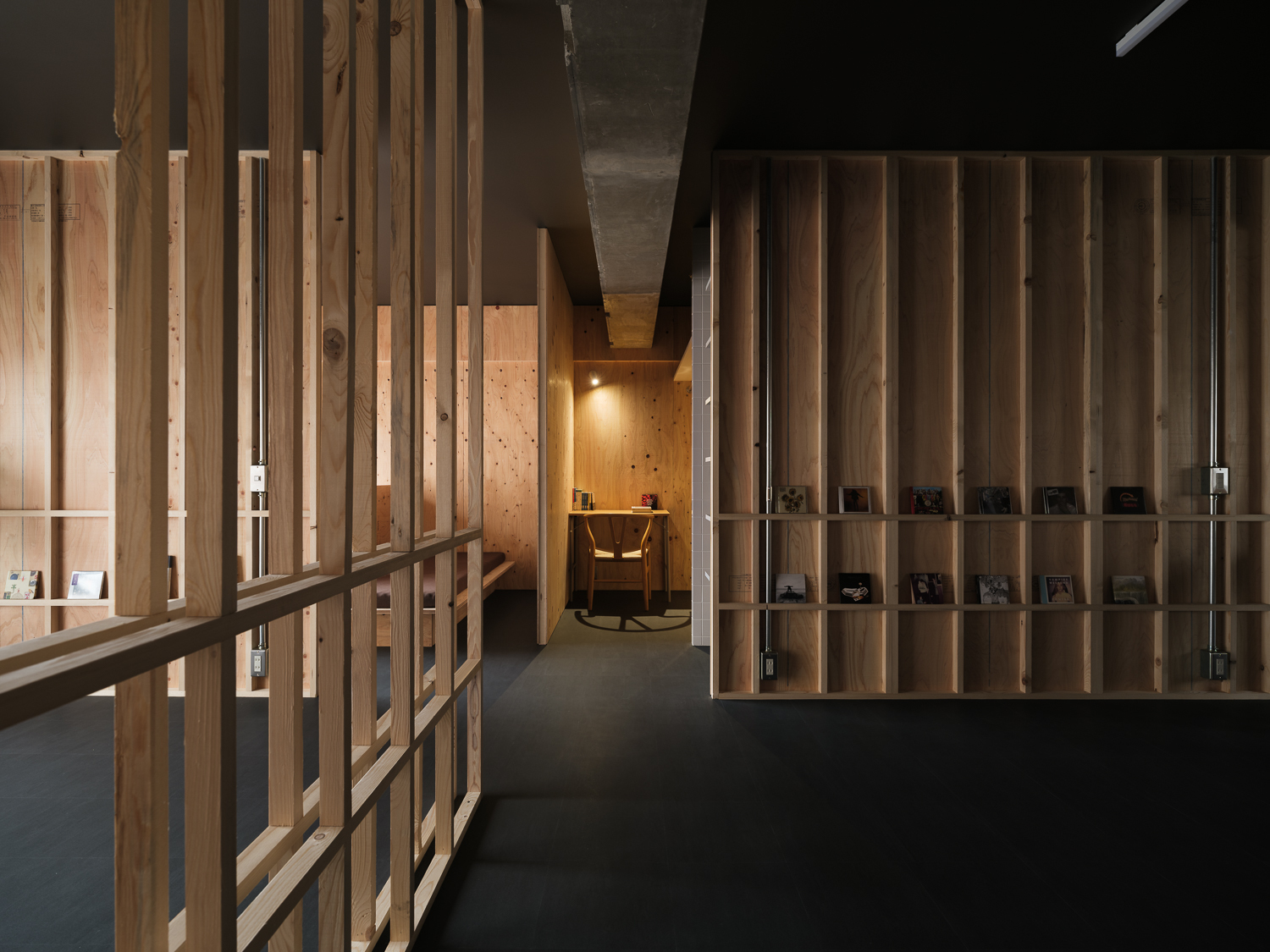 Corridor with timber slat screens flanking both sides leading toward an illuminated workspace