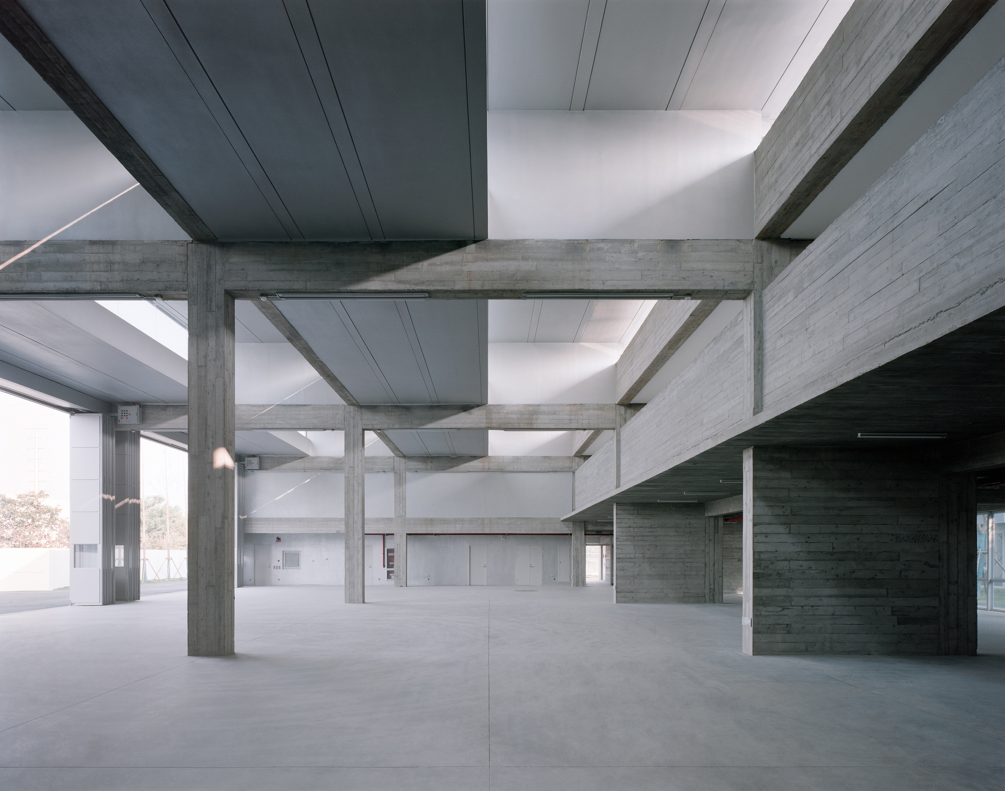 Exposed concrete structural grid with board-formed columns and beams beneath metal ceiling panels