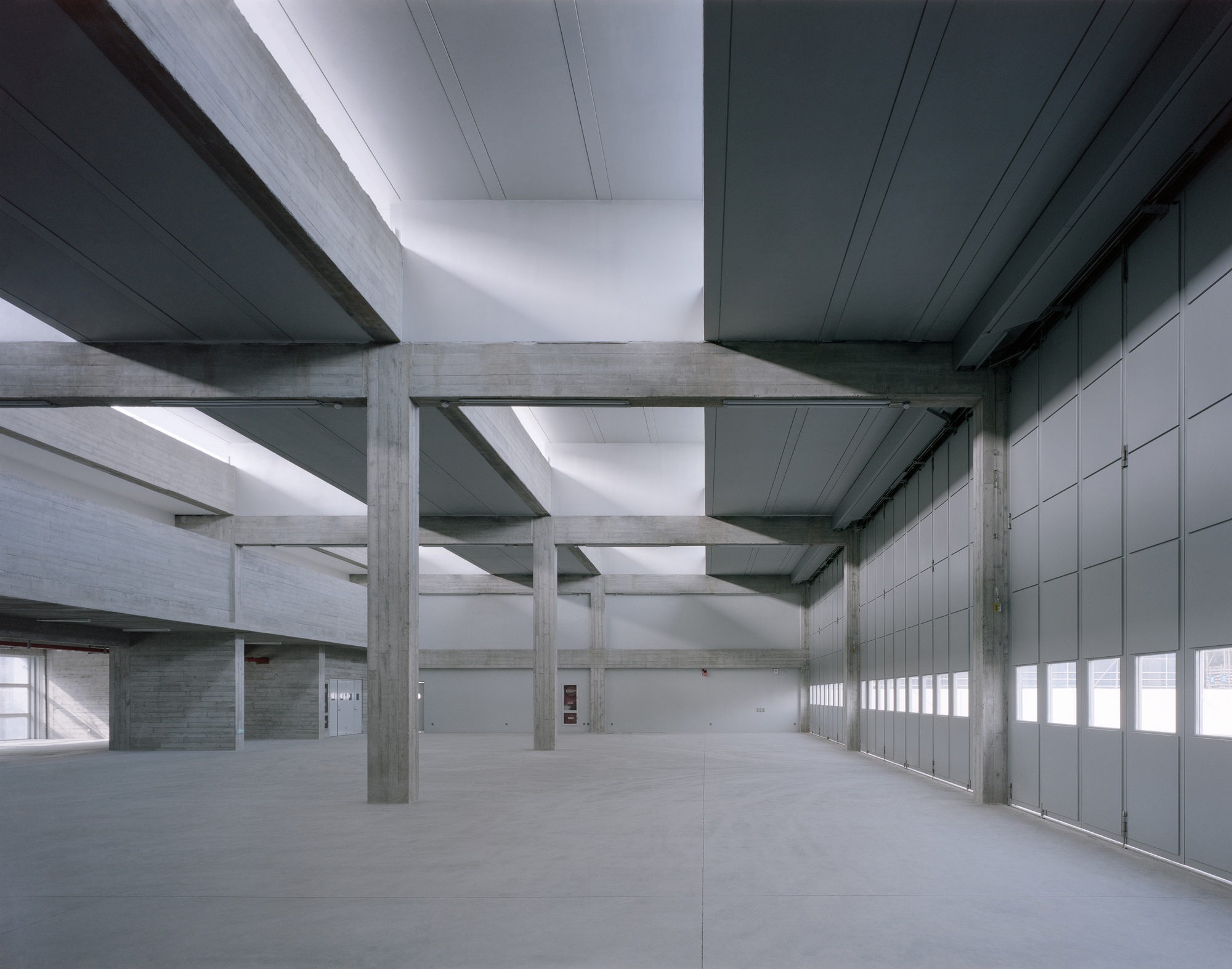 Interior view of concrete beam and column structure with continuous clerestory lighting and grey panel wall