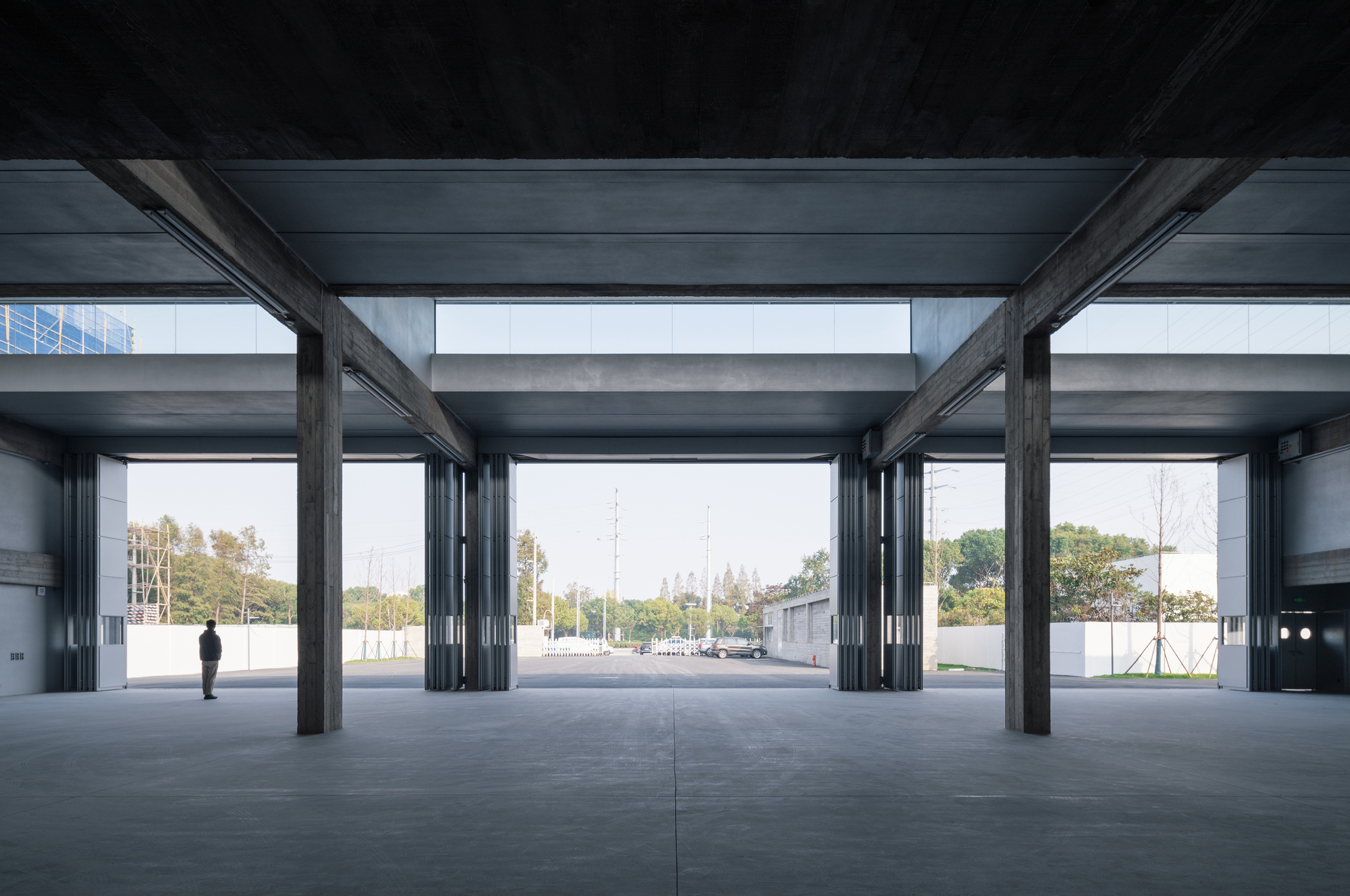 Ground floor interior with exposed steel columns and beams framing views to the outdoor courtyard