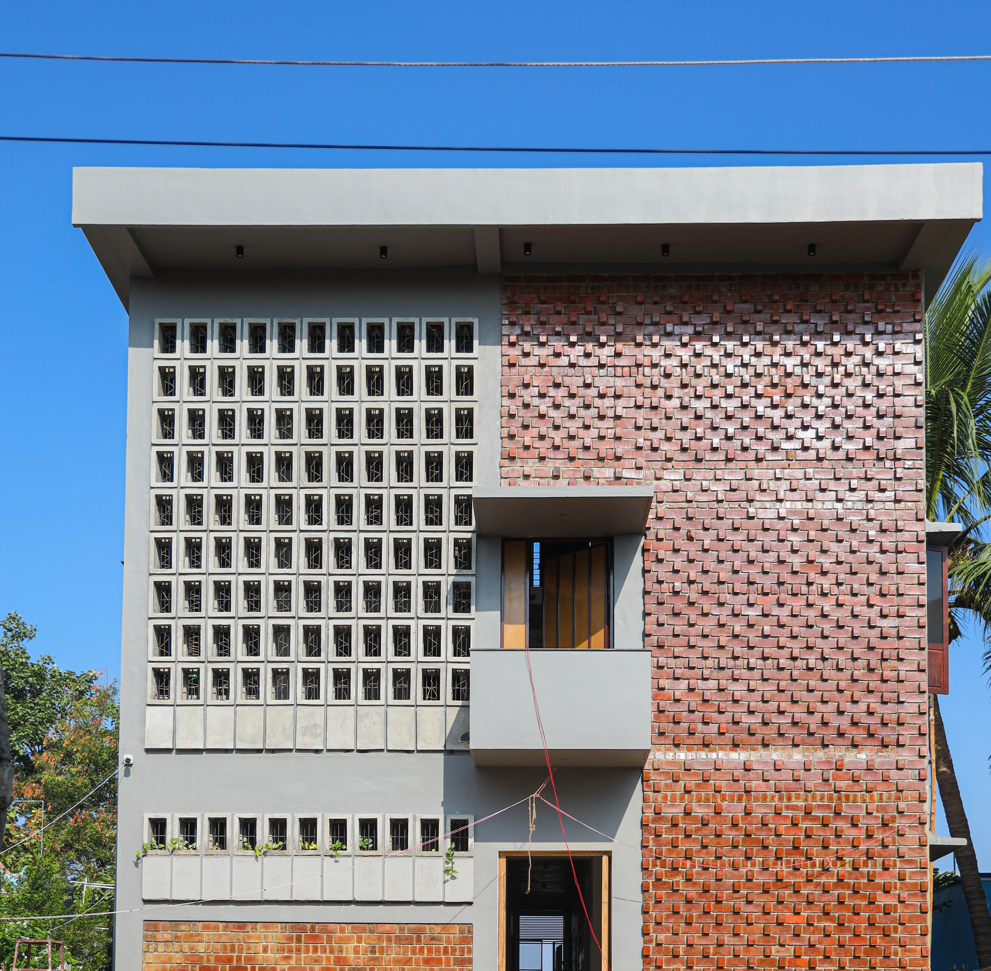 Front elevation showing white concrete block screen and staggered brick facade against bright blue sky