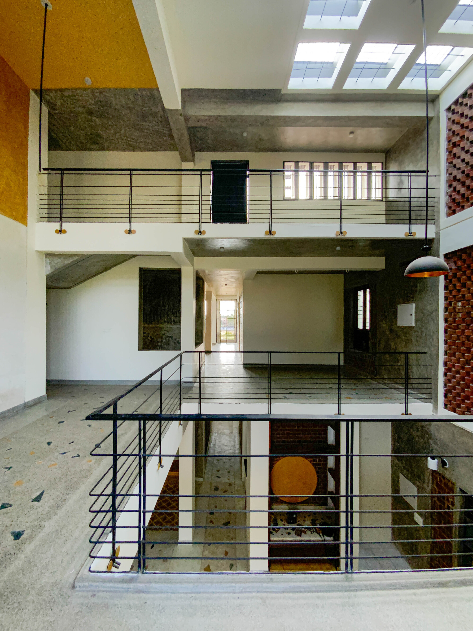 Multi-level atrium looking down through steel railed balconies to terrazzo floor and lower level openings