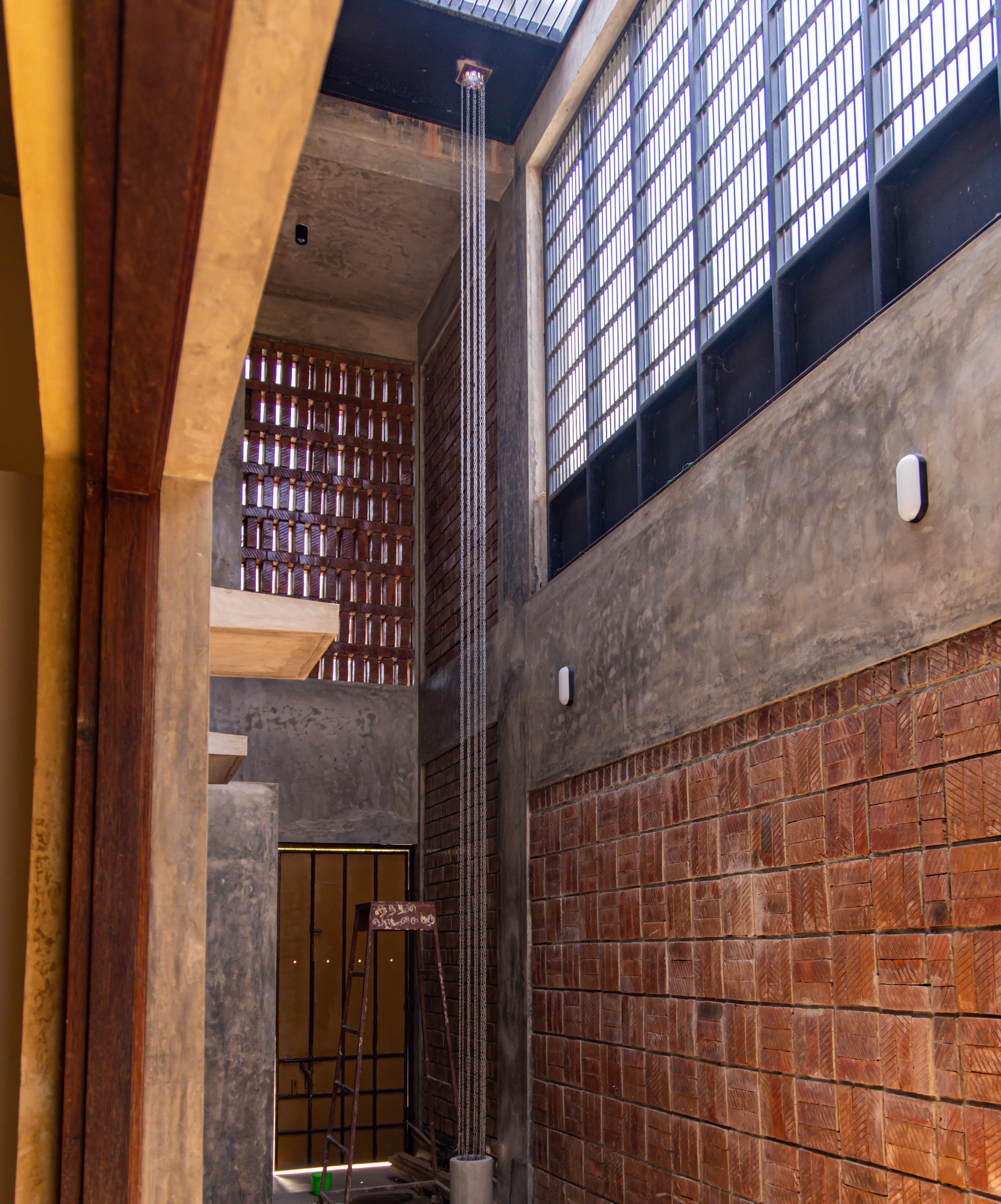 Triple-height atrium with exposed brick walls, perforated screens and fluted concrete column