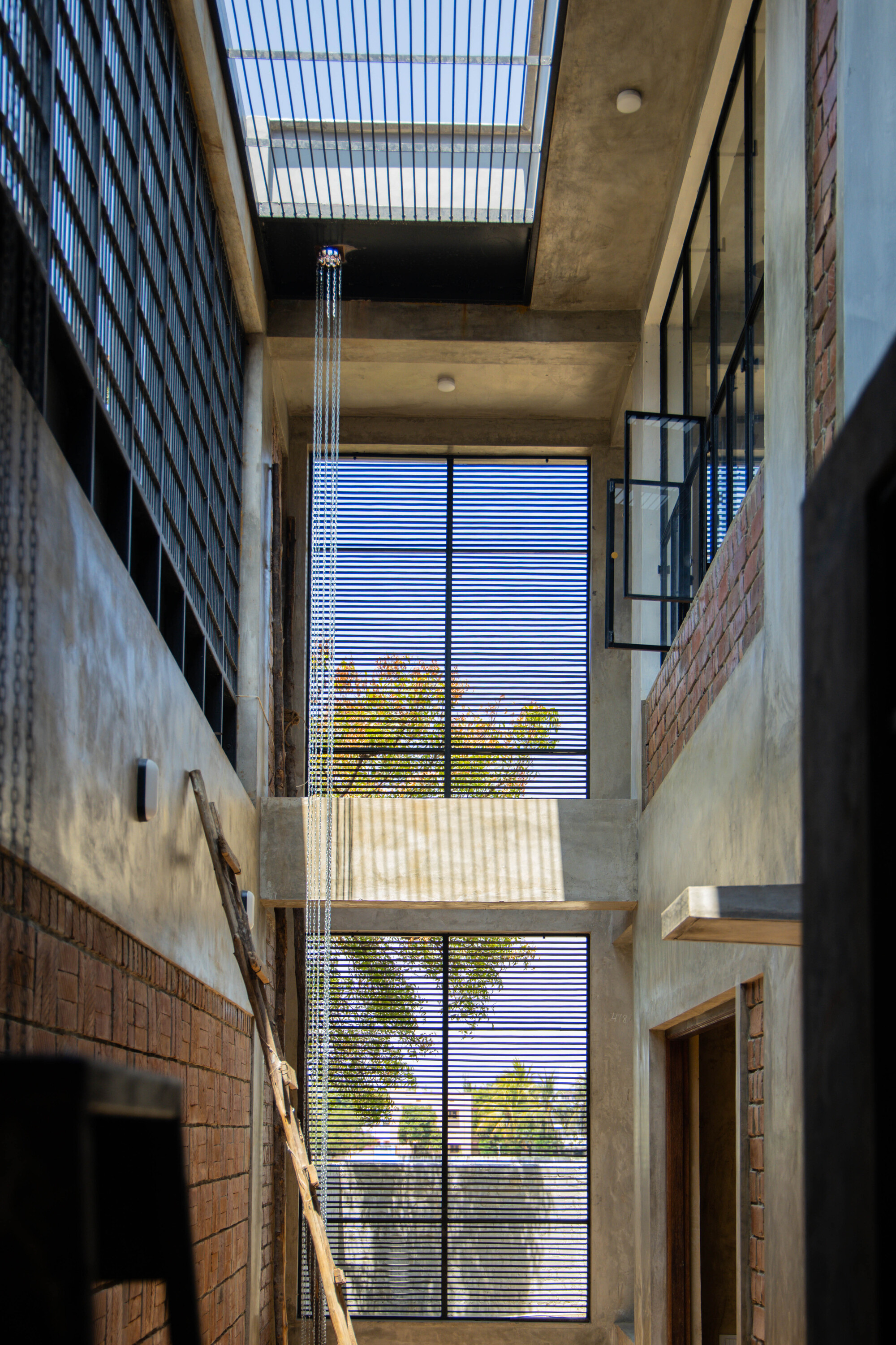 Double-height interior courtyard with horizontal louvered screen framing trees outside
