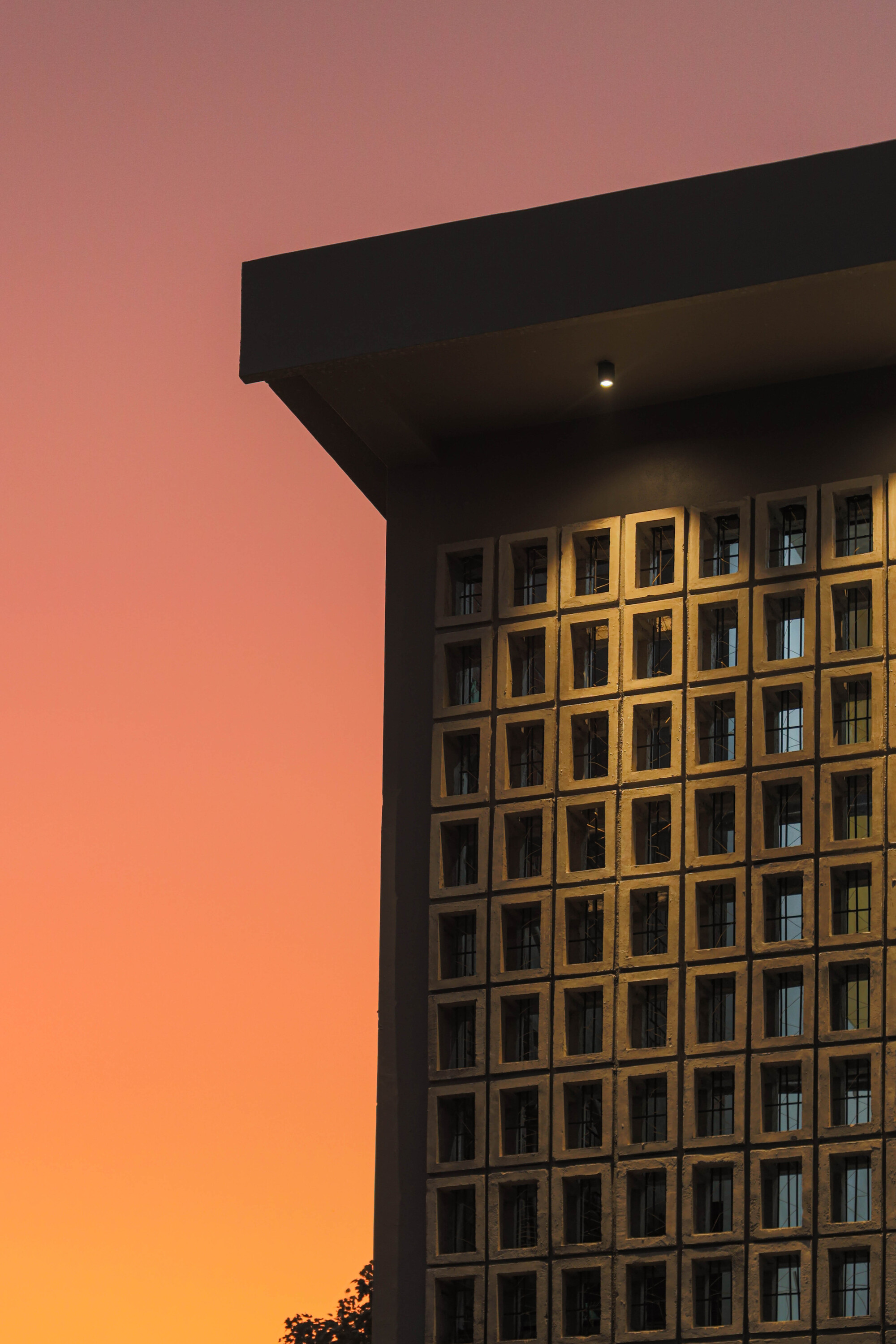 Timber lattice facade beneath a deep overhang against a vibrant orange sunset sky