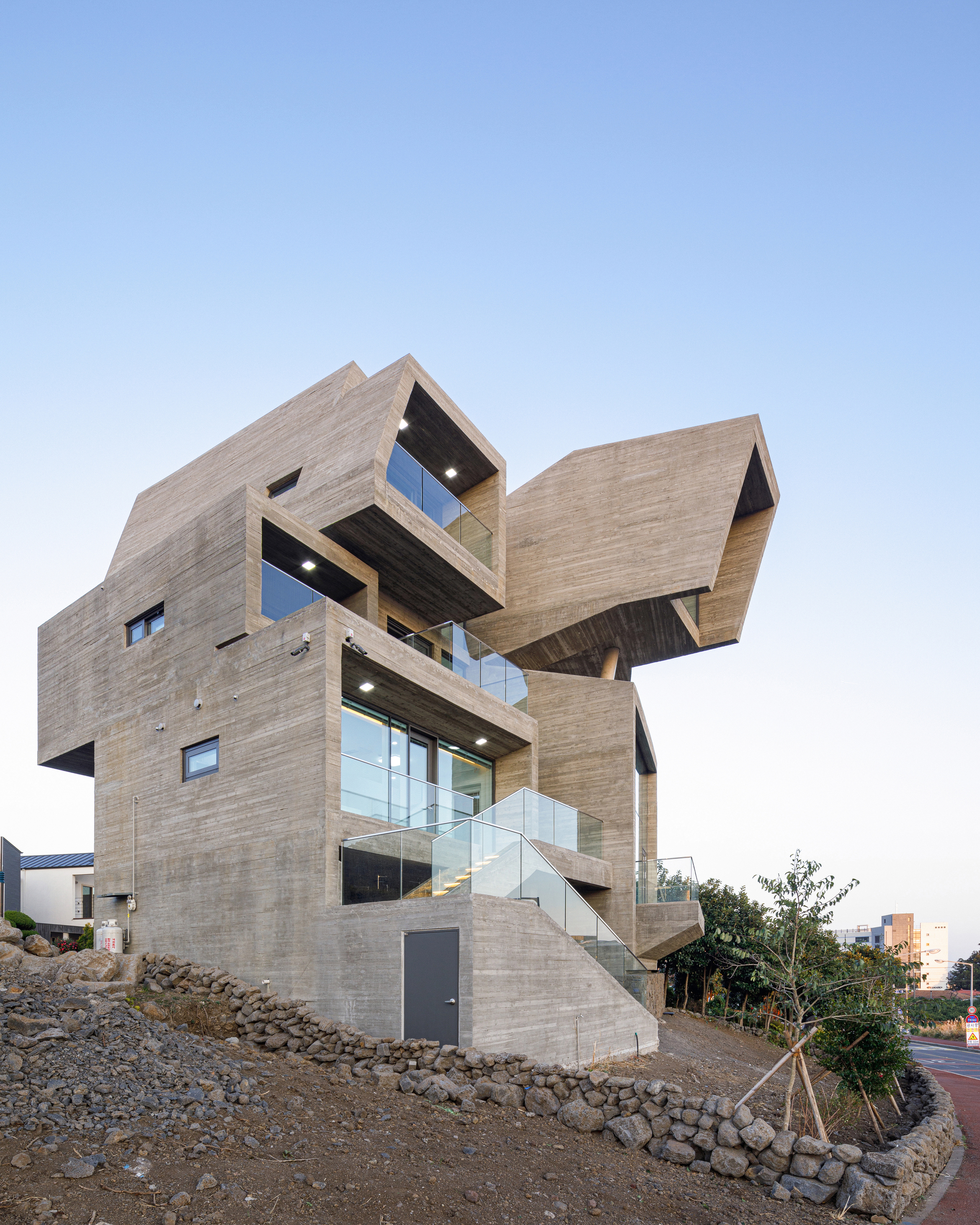 Board-formed concrete facade with cantilevered balconies and exposed soffits at dusk