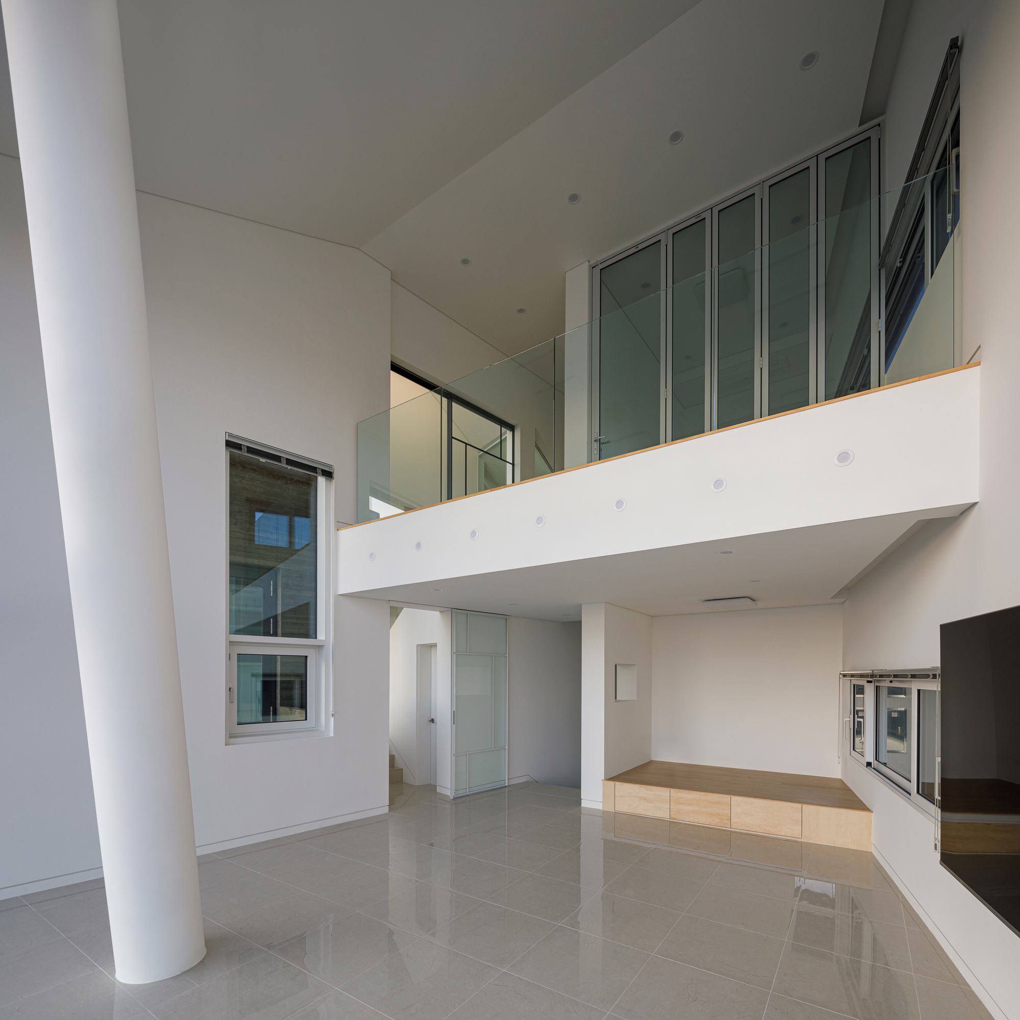 Open living space with a mezzanine gallery above and polished tile flooring below