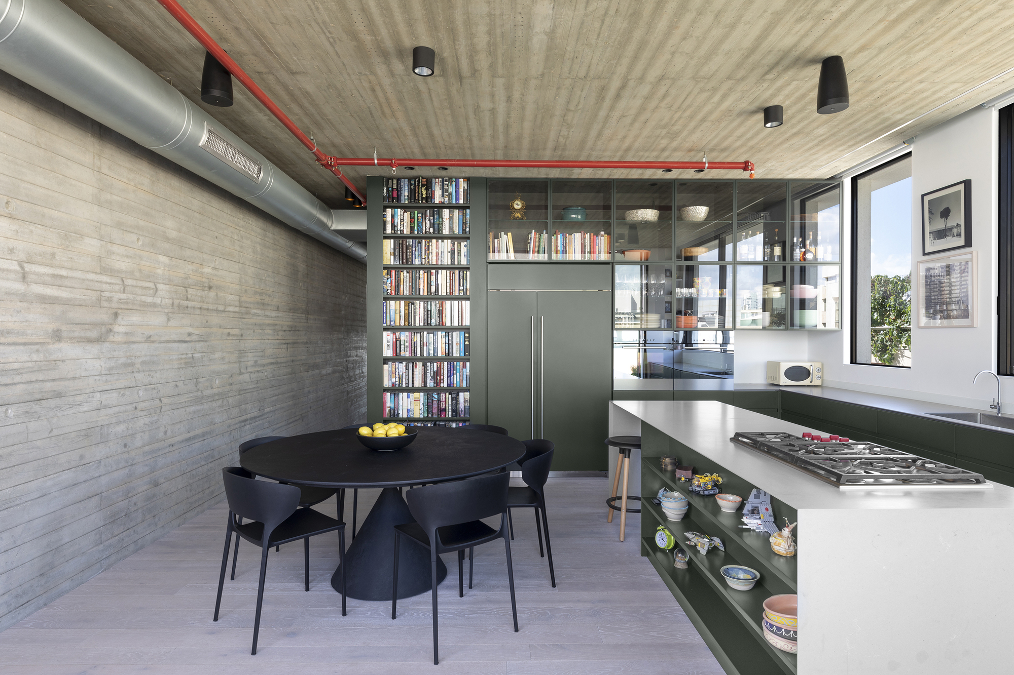 Open kitchen and dining area with exposed red conduit and ductwork beneath a board-formed concrete ceiling