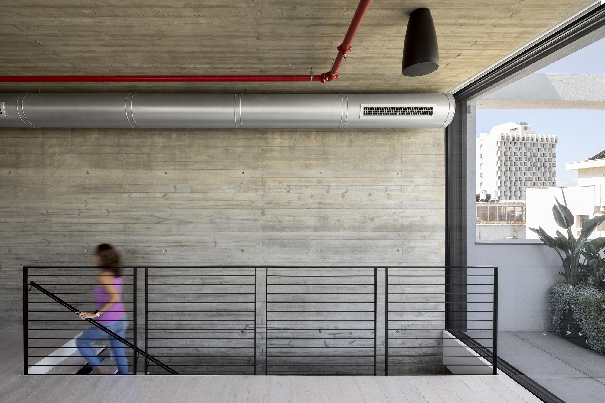 Upper level landing with horizontal cable railing and blurred figure descending the staircase