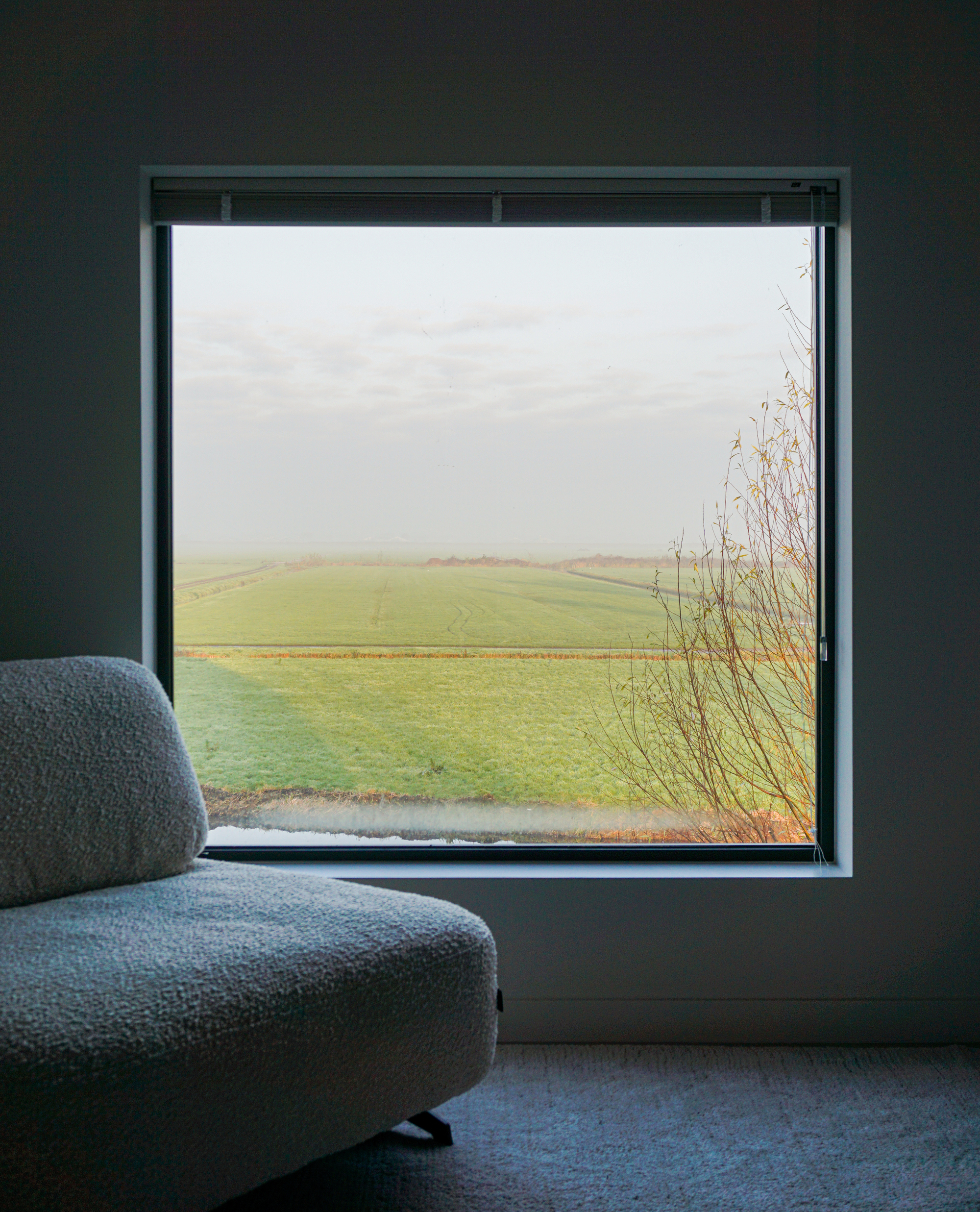 Square window seat overlooking green farmland and grasses in misty weather