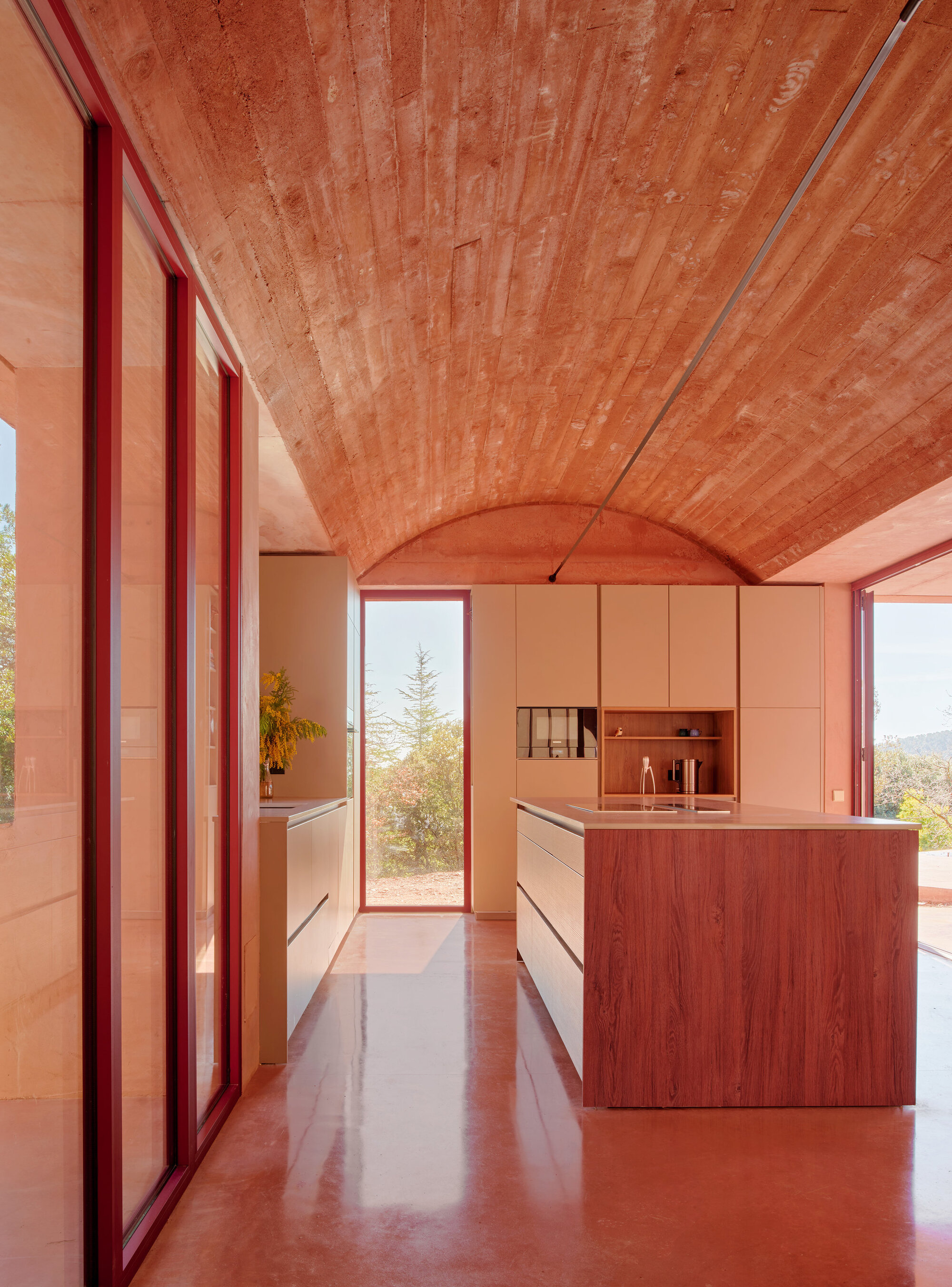 Kitchen with timber island, polished terracotta floor and vaulted tile ceiling beneath glazed openings