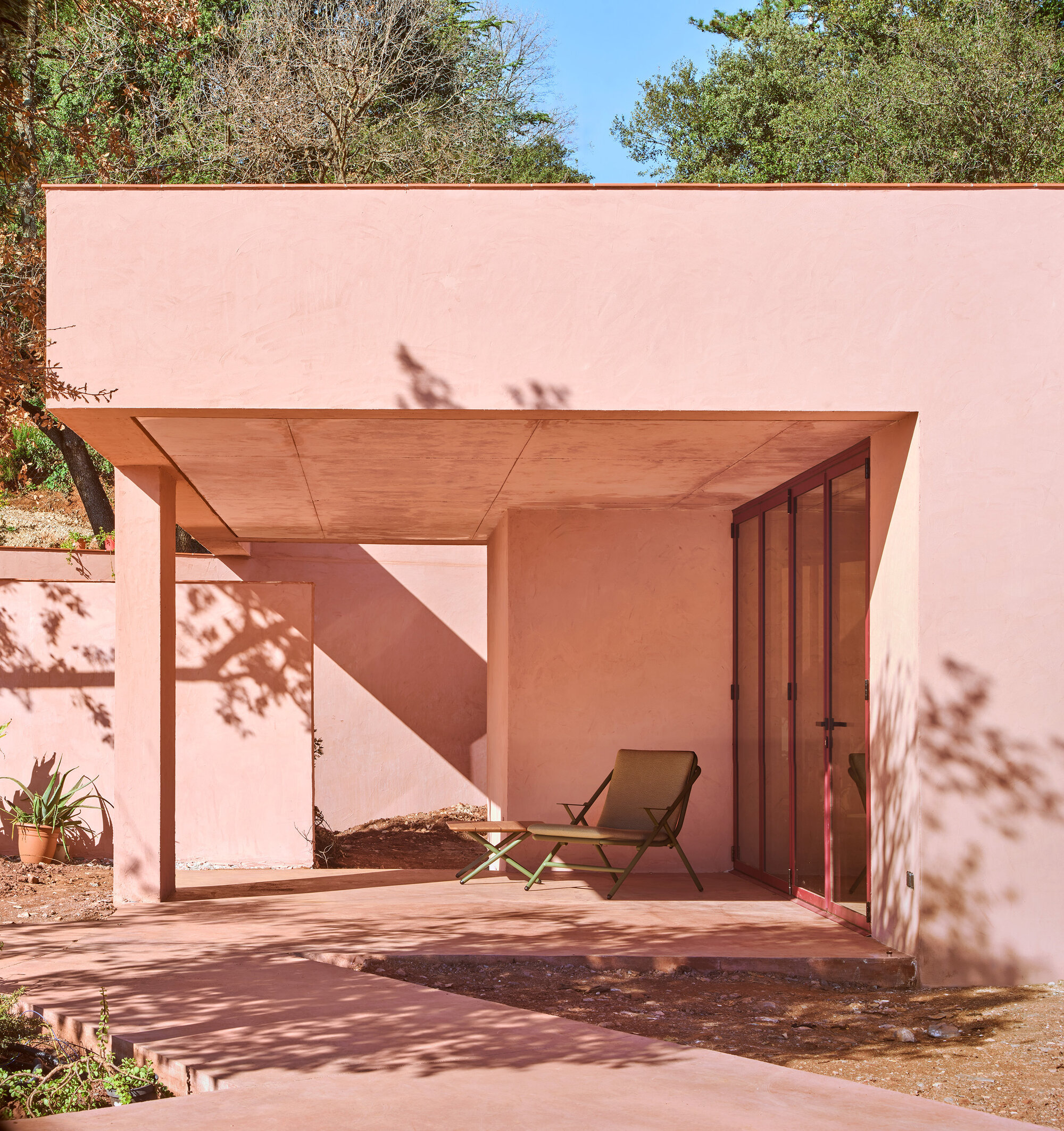 Covered terrace with timber ceiling panels and folding chair dappled in afternoon shade