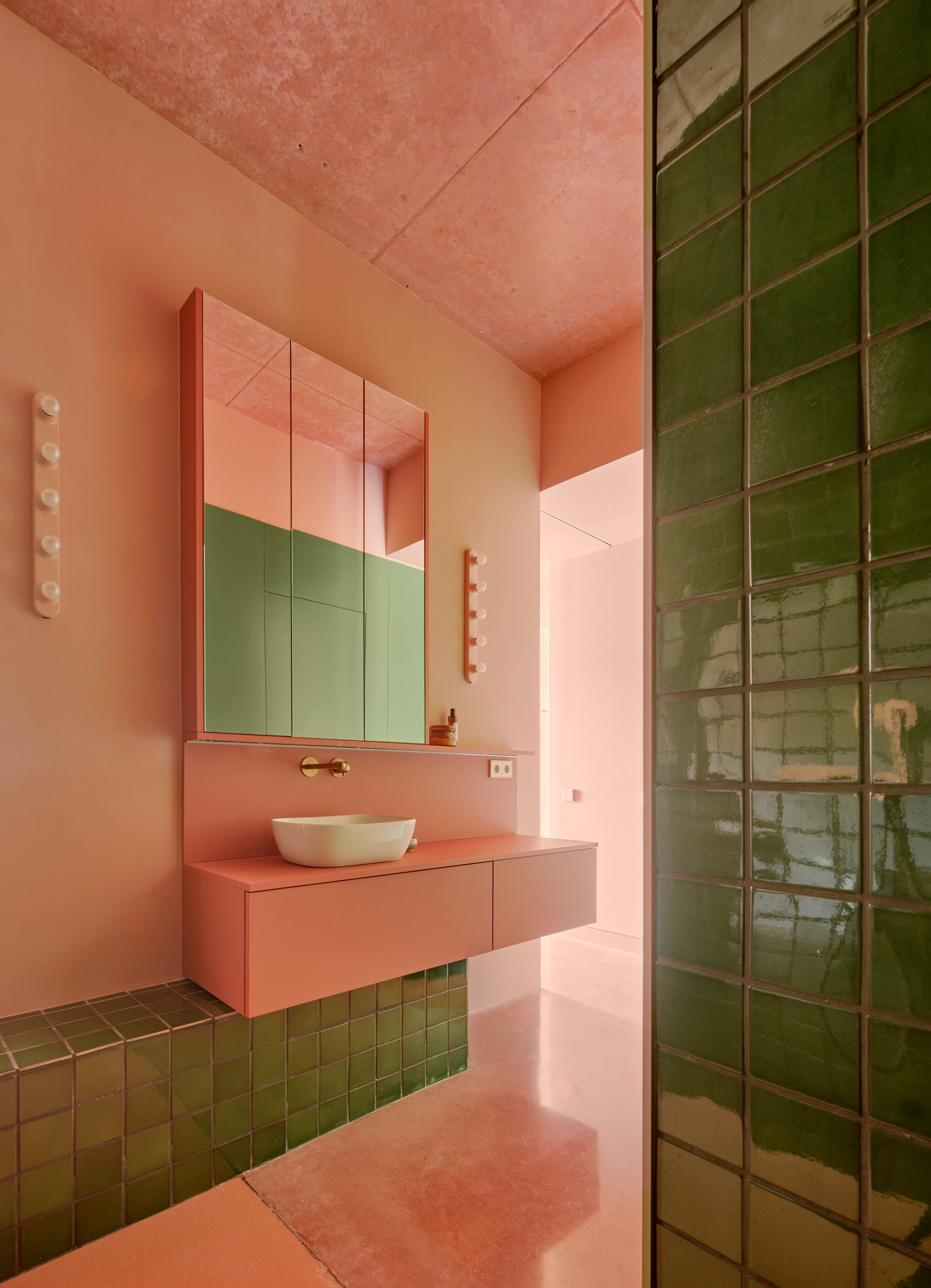 Bathroom with pink floating vanity, green glazed tile shower wall and mirrored cabinets