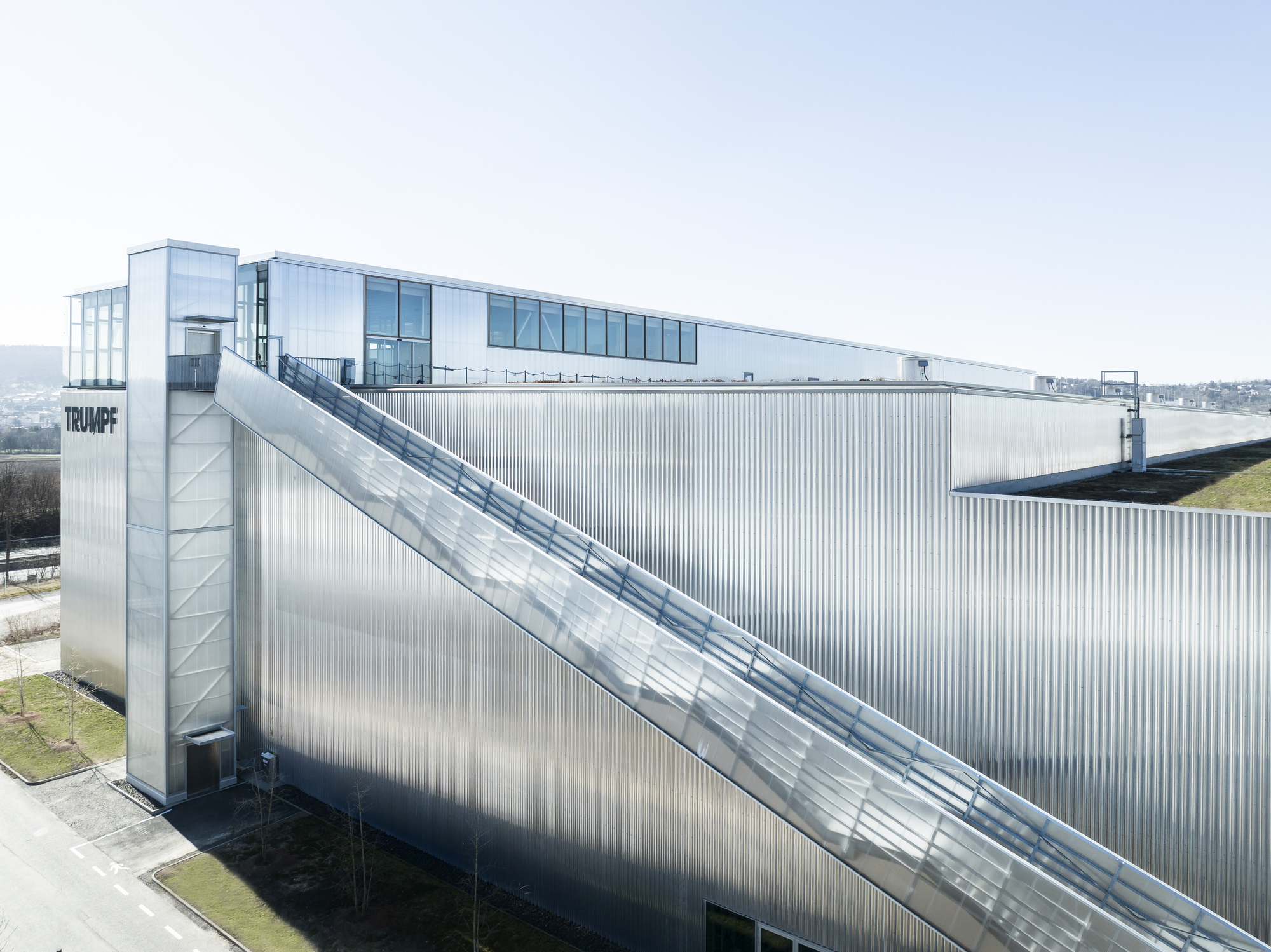 Corrugated metal facade with diagonal exterior staircase leading to a glazed upper volume