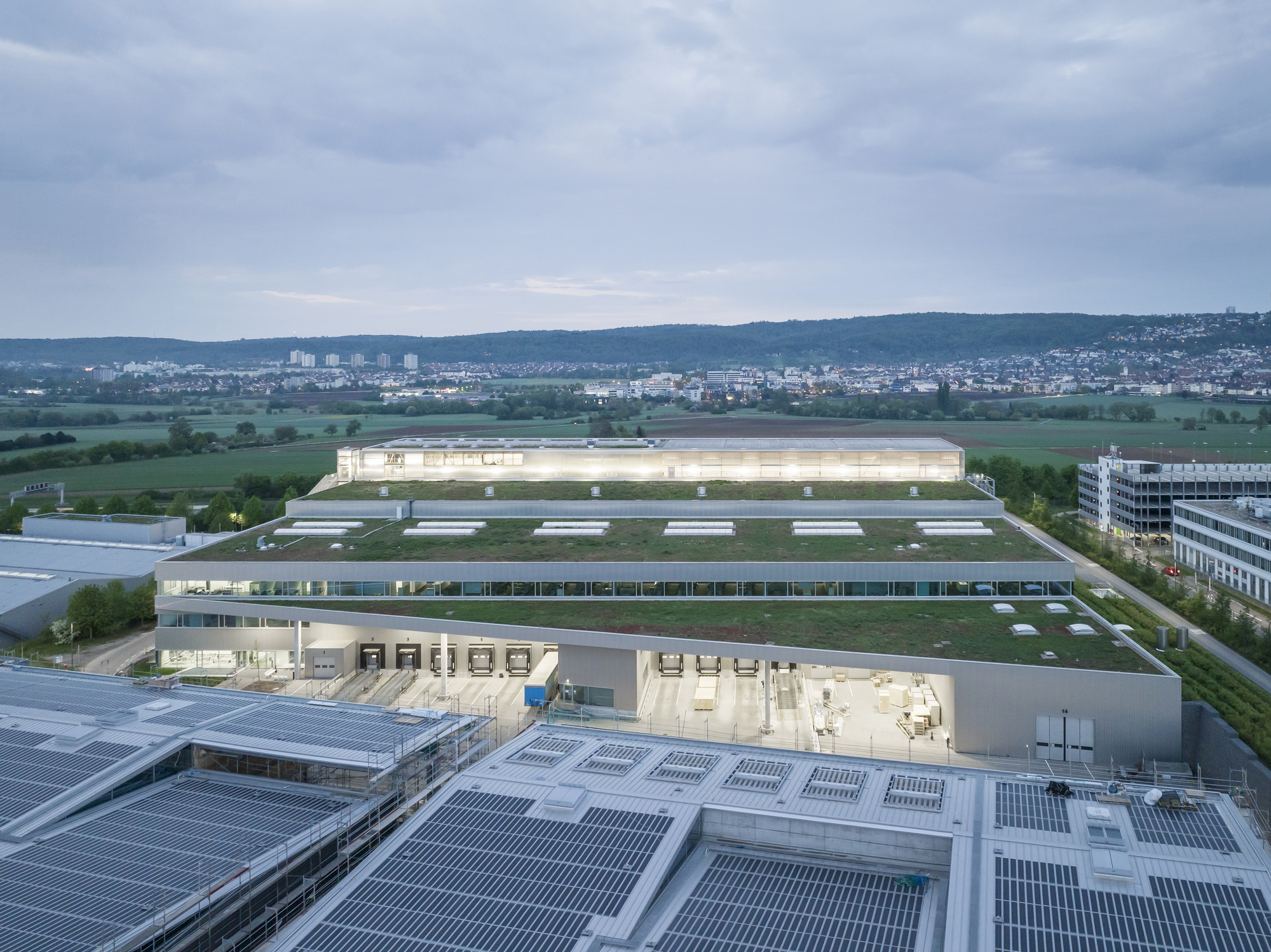 Aerial view of the industrial complex with photovoltaic arrays on rooftops at dusk
