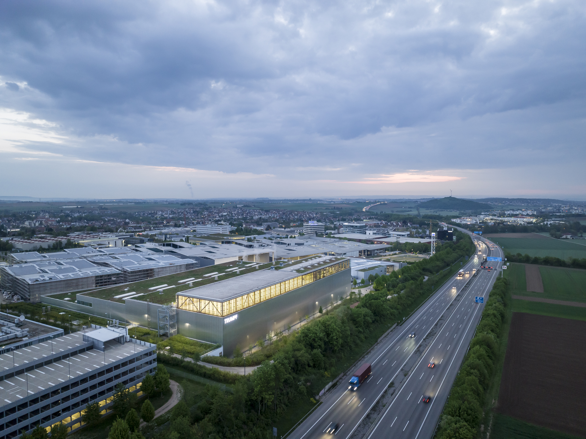 Aerial view of the illuminated industrial building along the highway at dusk