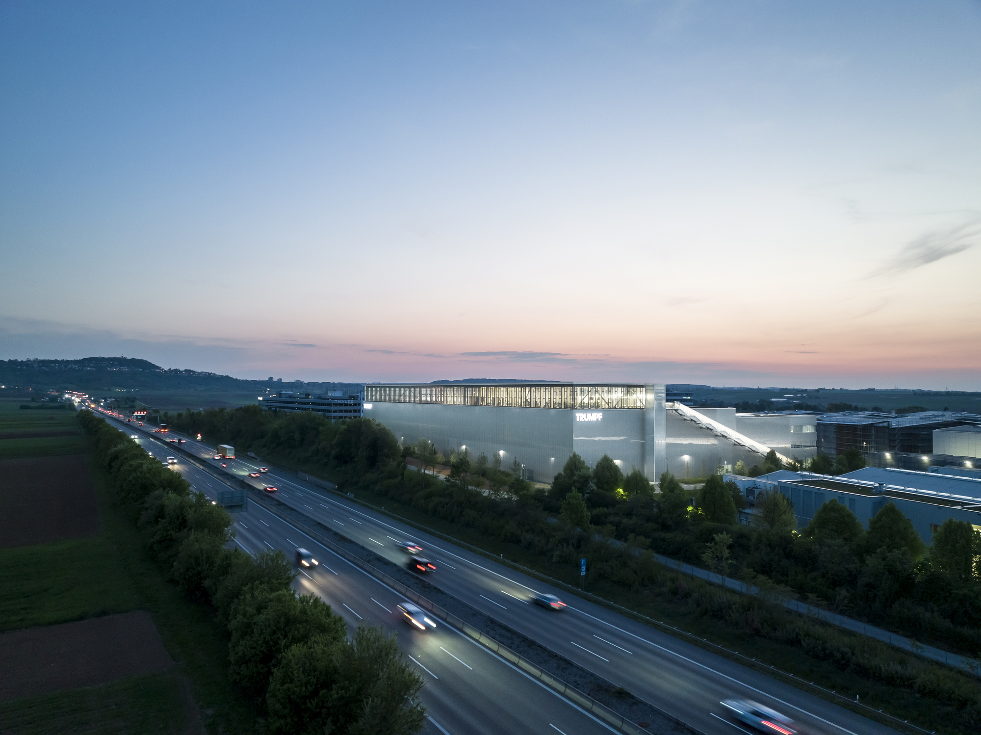 Long exposure view of the illuminated facility beside the highway with passing traffic