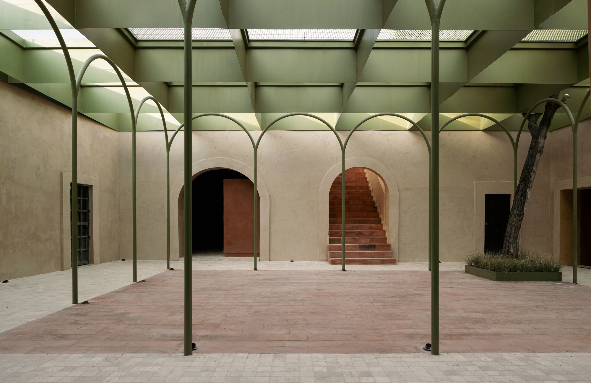 Skylit courtyard with arched steel colonnade framing arched doorways and a brick staircase