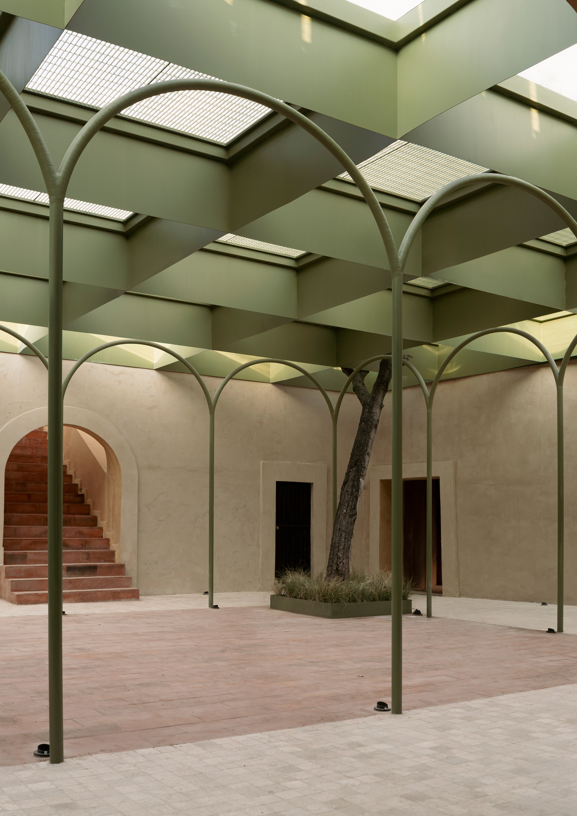 Courtyard with slender green steel arches supporting a green coffered ceiling with translucent skylights