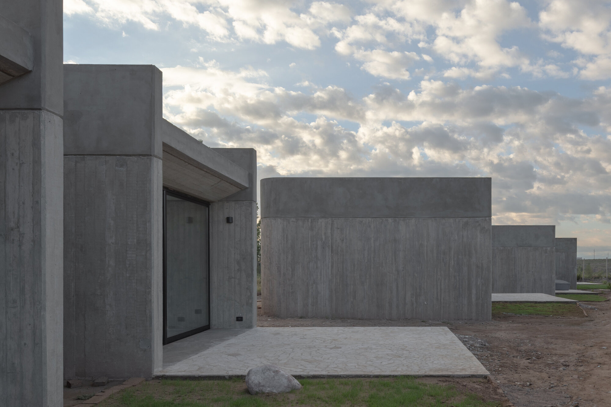 Boardformed concrete courtyard with stepped volumes under a cloudy afternoon sky