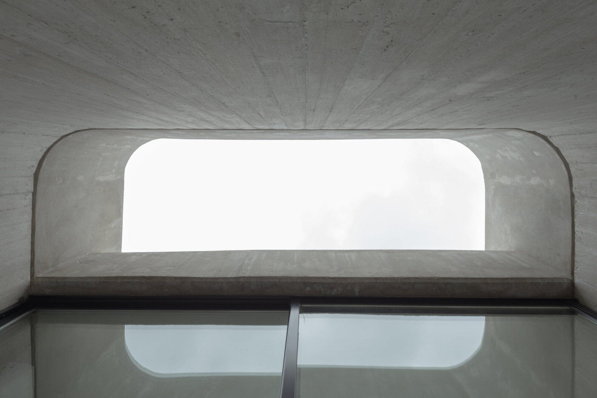 Interior view up through curved concrete vault with rounded window opening overhead
