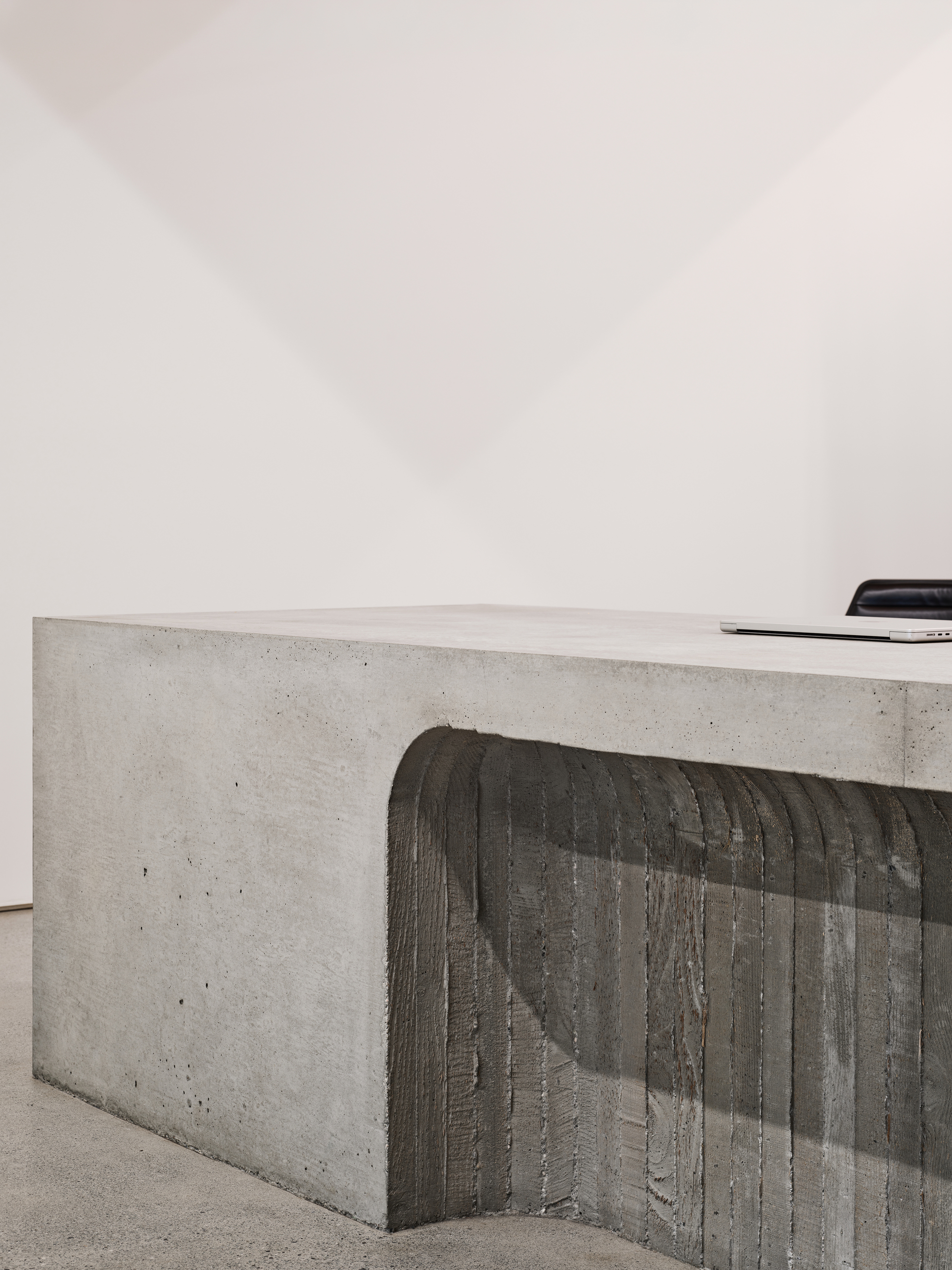 Close-up of board-formed concrete counter with vertical timber texture against a white wall