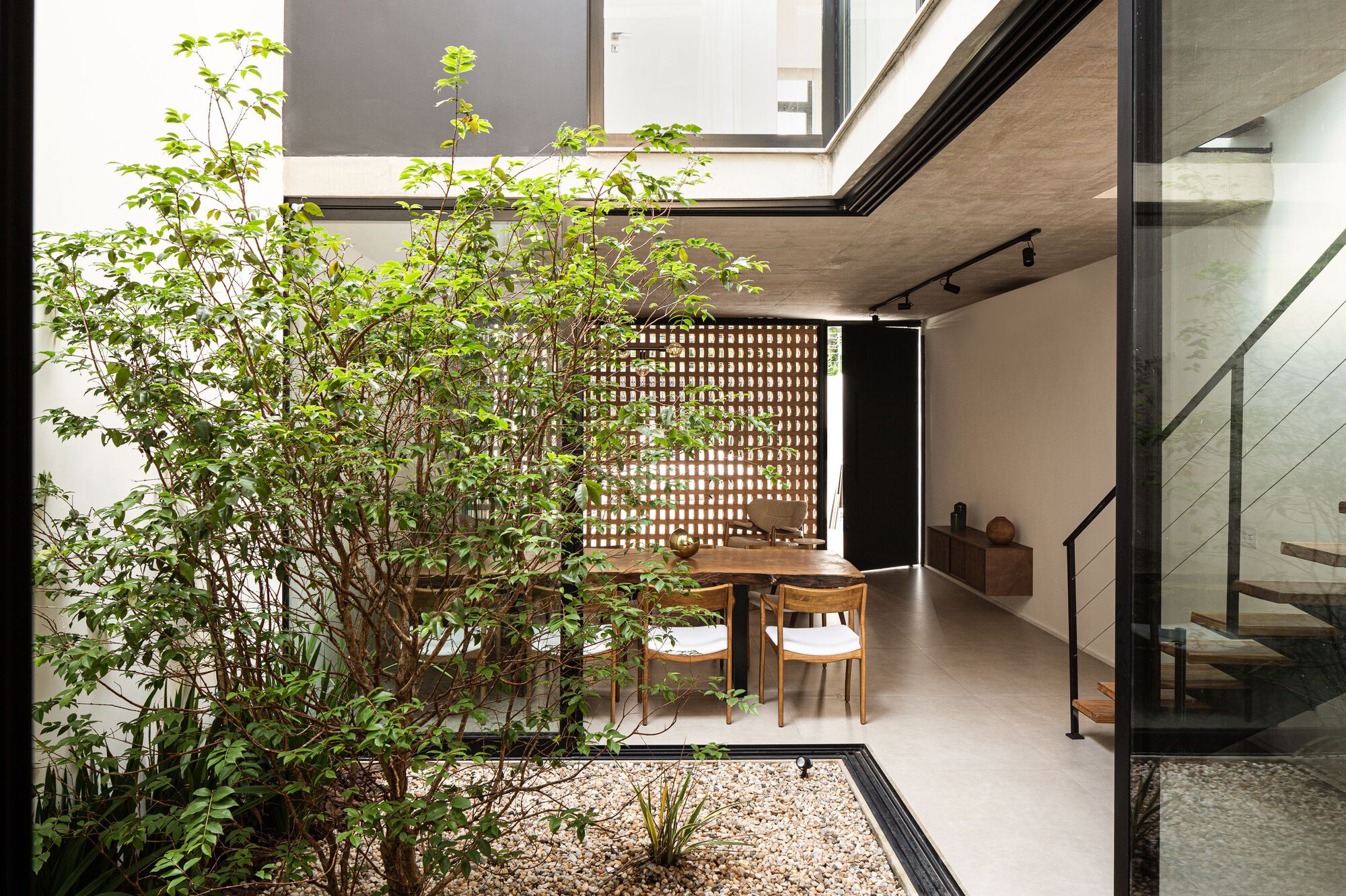 Interior courtyard with planted tree, gravel bed and perforated brick screen wall