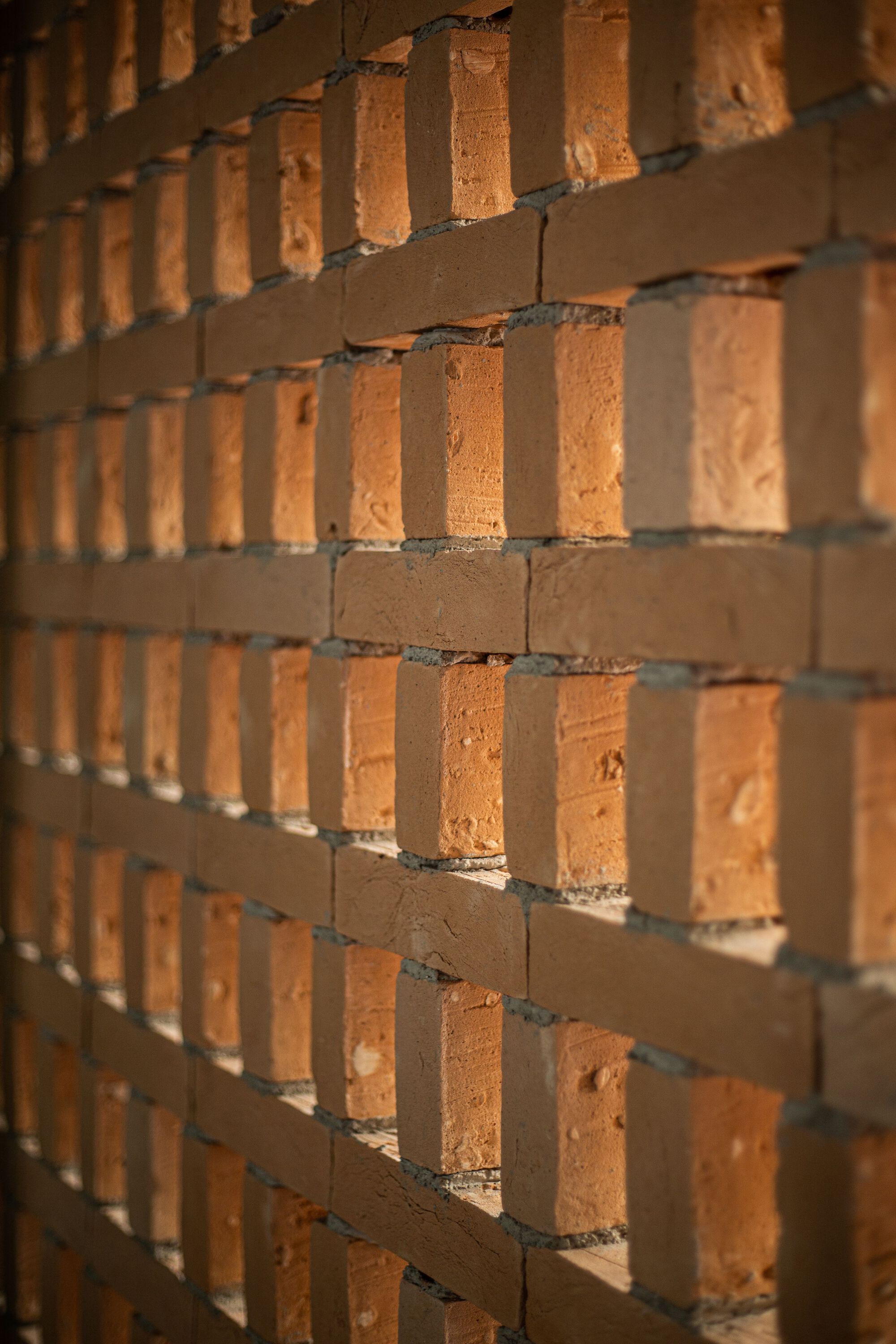 Angled view of stacked brick corners showing mortar joints and textured face in raking sunlight