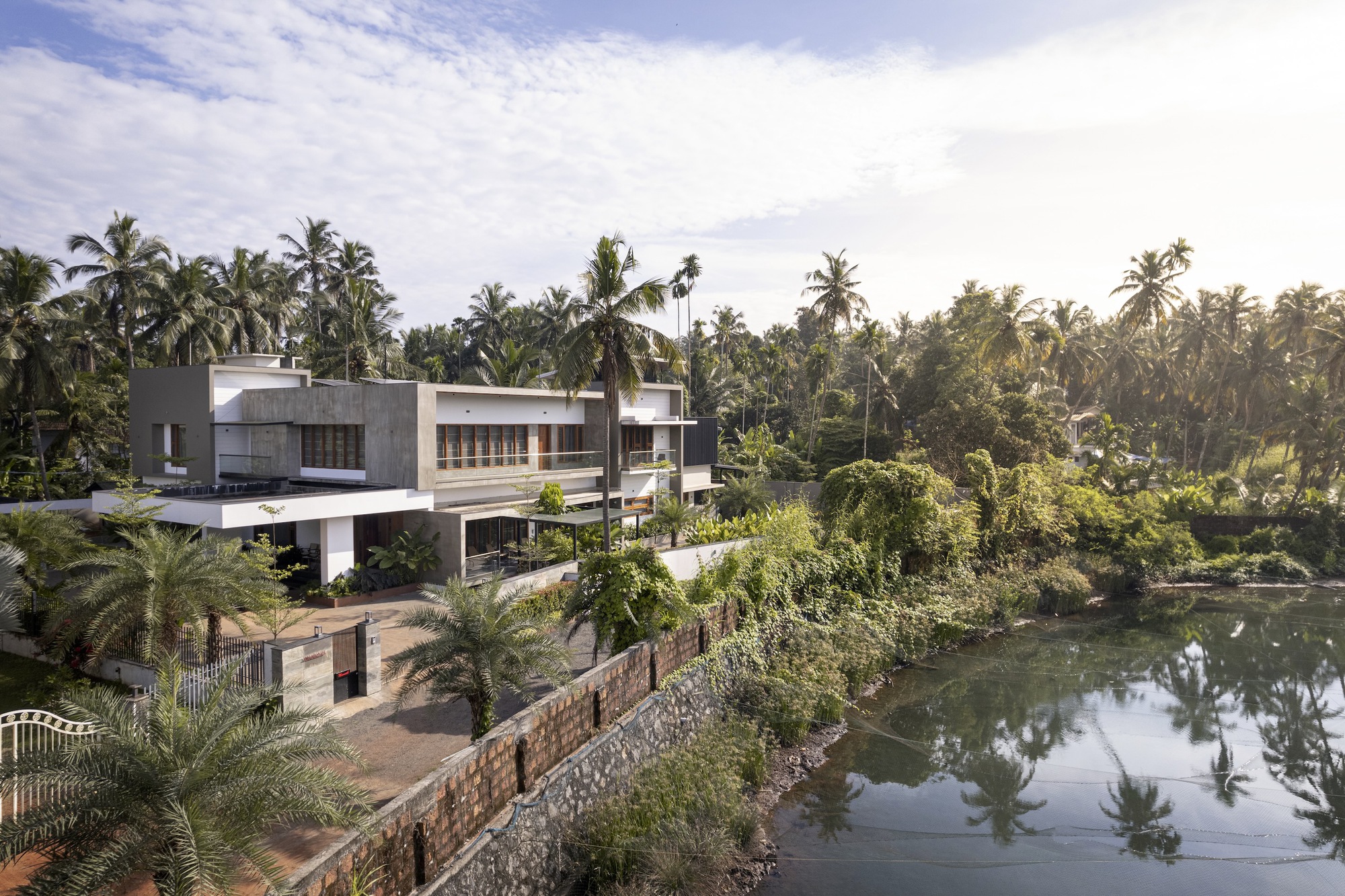 Elevated view of the terraced concrete volumes stepping down to a pond bordered by tropical vegetation