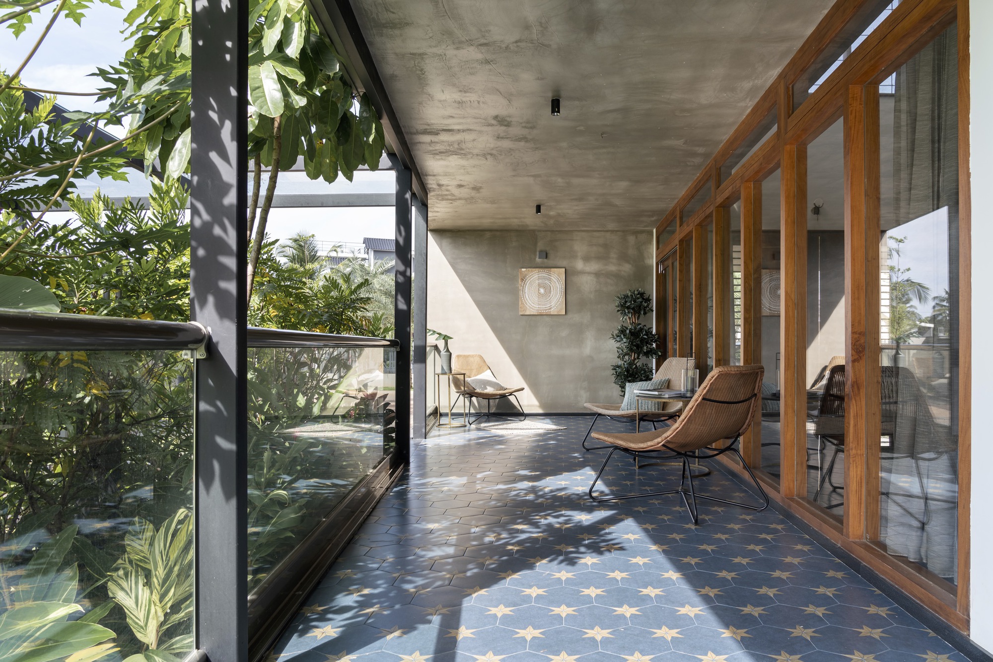 Covered terrace with patterned tile floor, concrete soffit, and timber sliding doors filtering afternoon sunlight