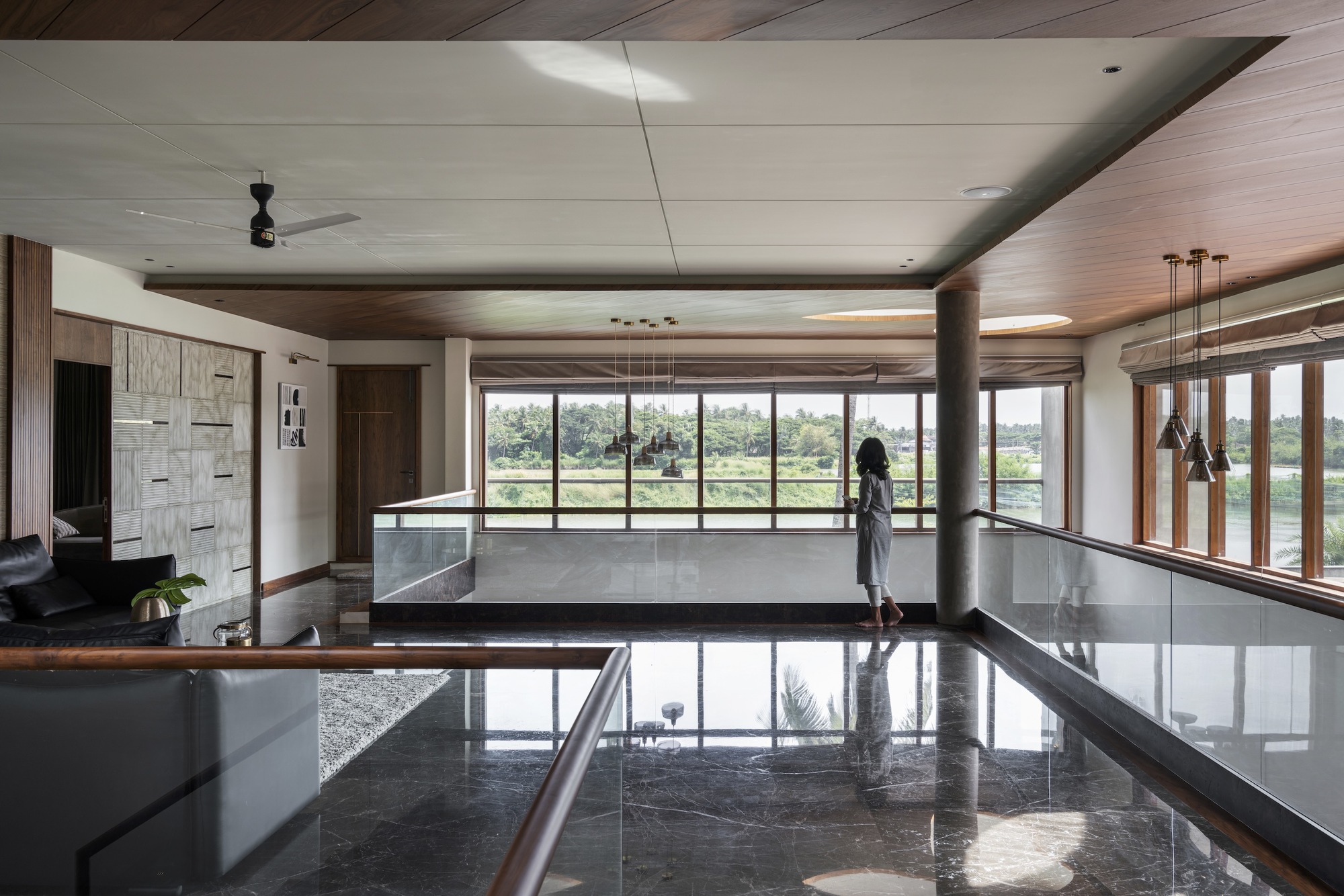 Upper-level interior with polished stone floor, timber ceiling panels, and a person standing at the window