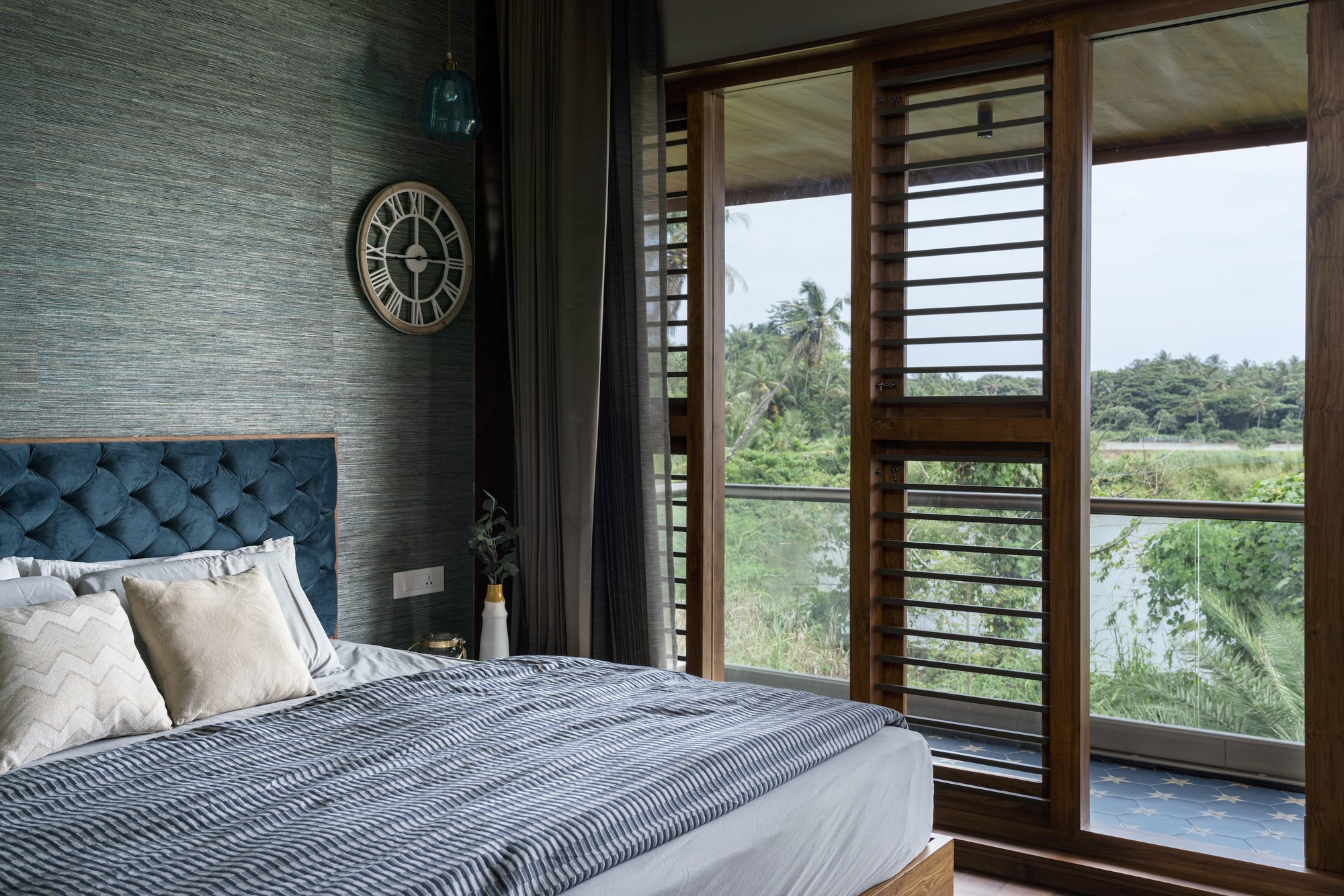 Bedroom with textured grey wall and timber louvered doors opening to a balcony beyond