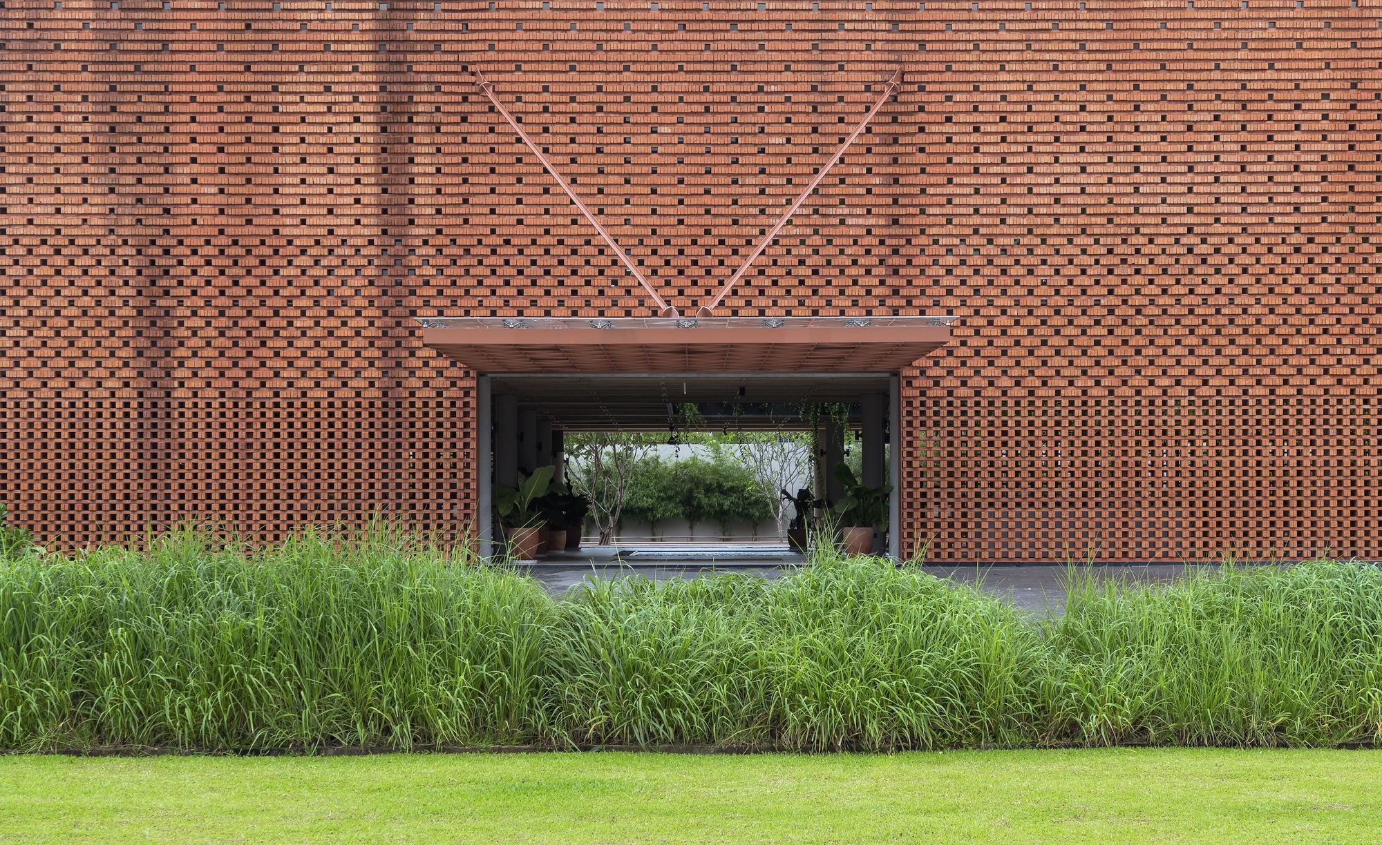 Straight-on view of covered entrance through perforated brick facade with geometric relief pattern