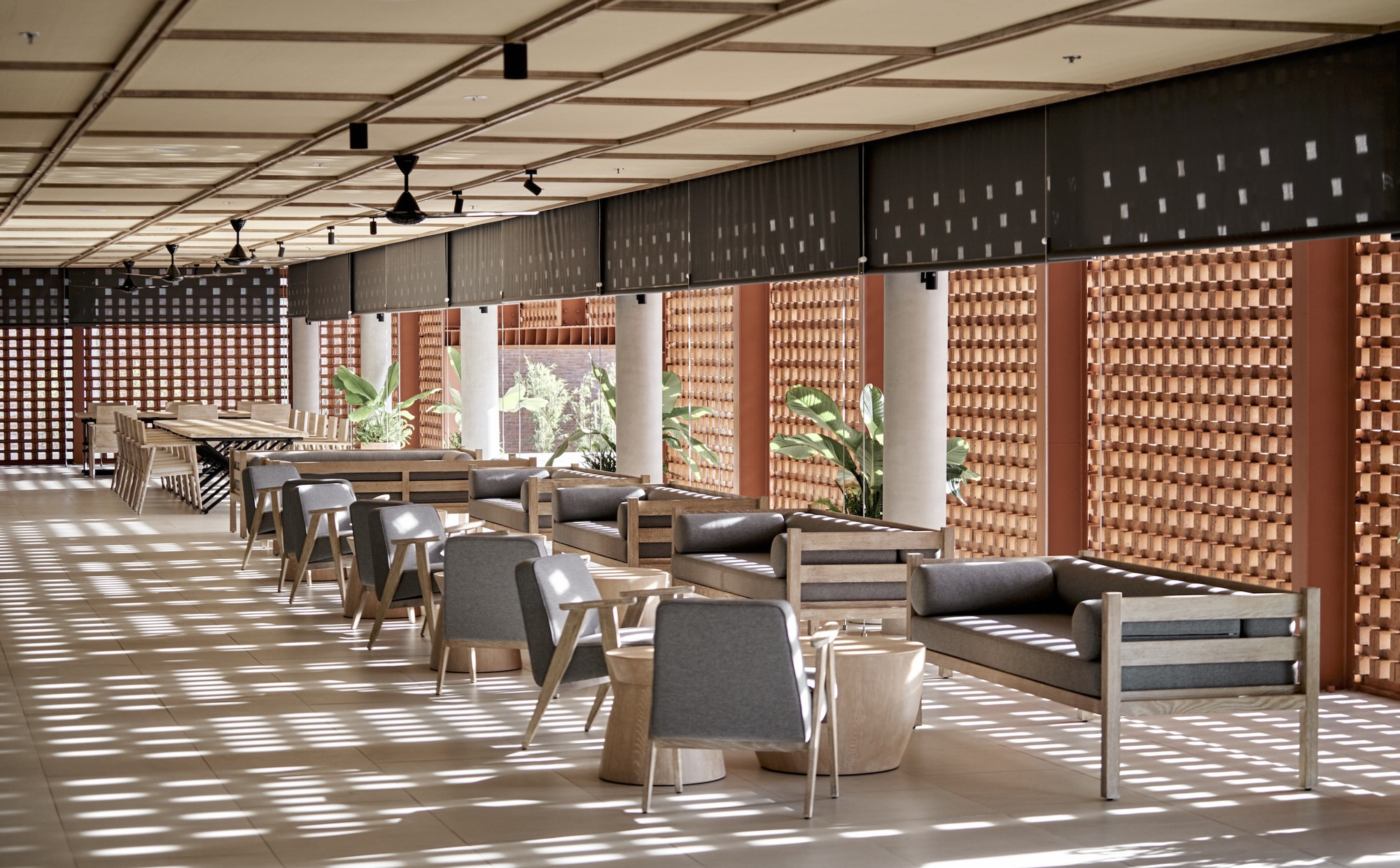 Dining area with lattice brick screens filtering dappled sunlight across timber furniture and pale terrazzo floor