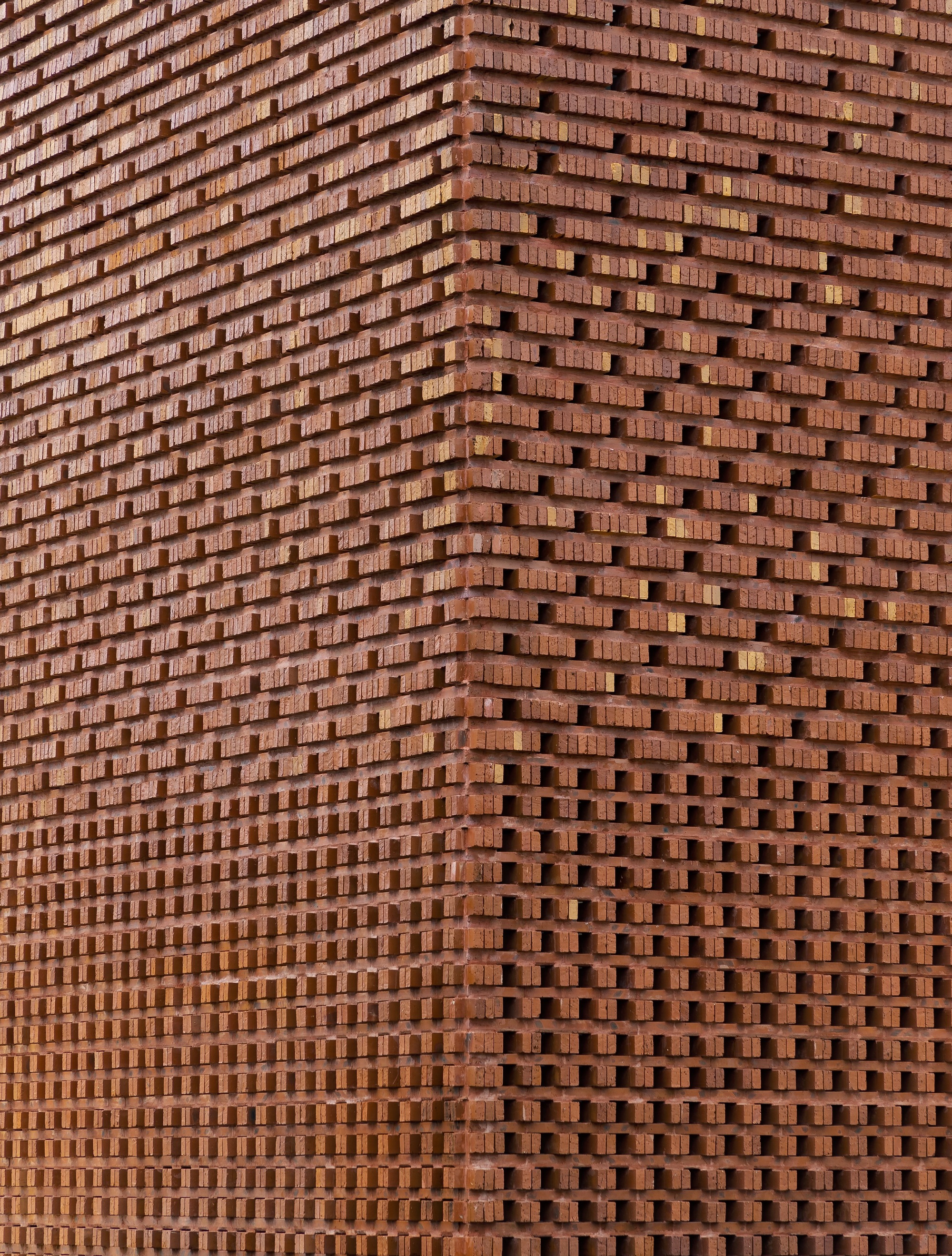 Close-up of the perforated brick screen showing undulating surface and staggered bond pattern