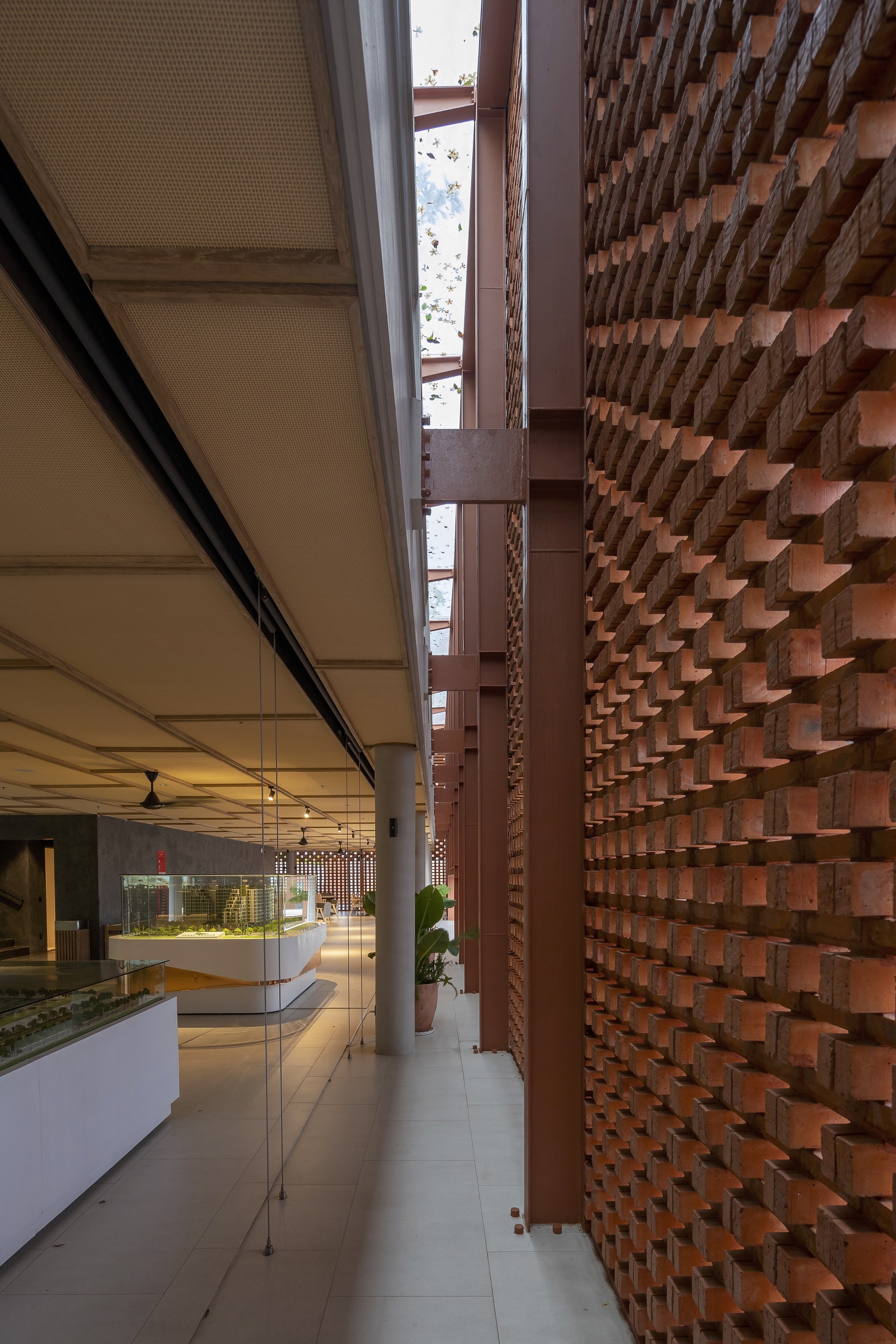 Narrow skylit passage between lattice brick wall and interior dining space with ceiling fans
