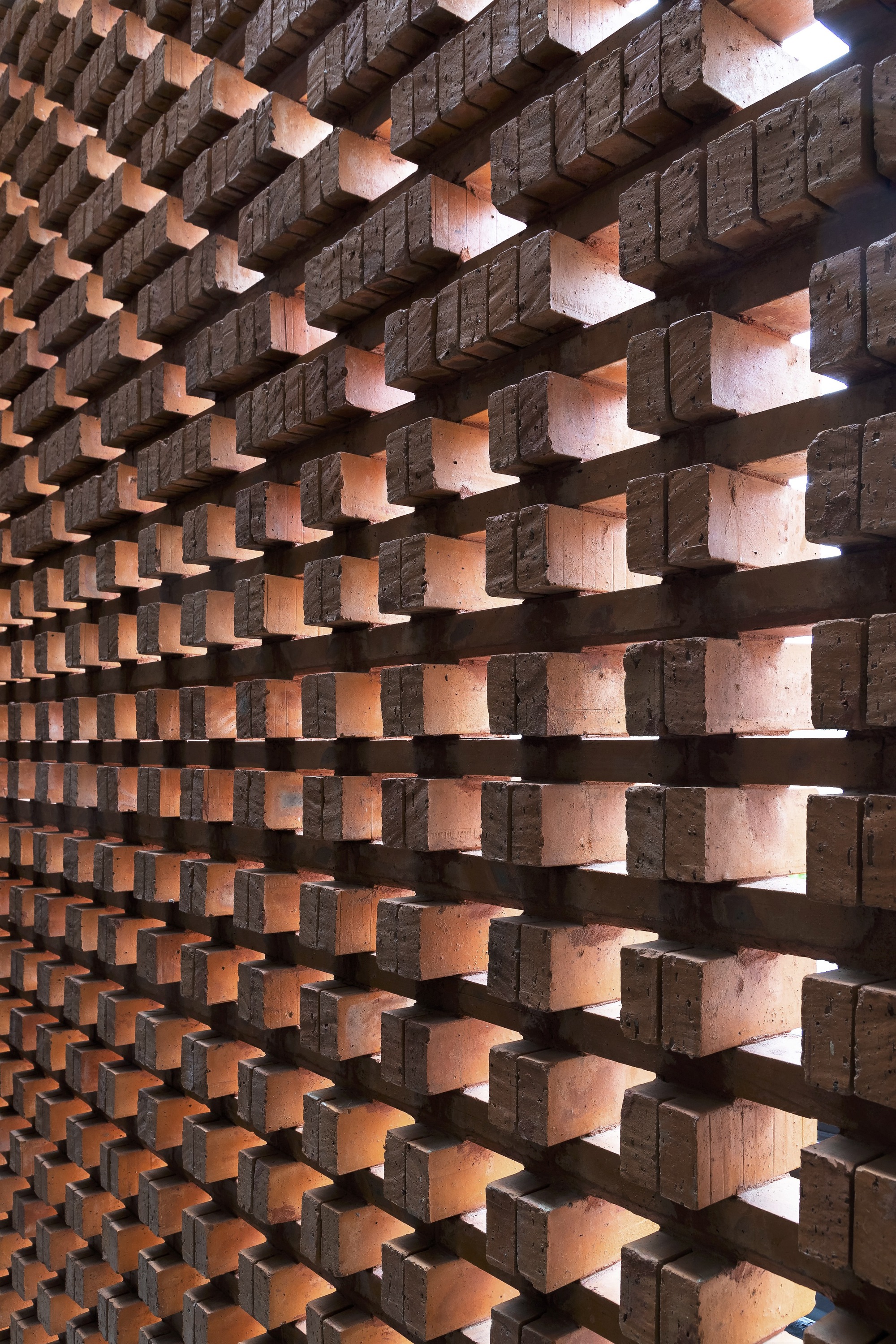 Perforated brick screen wall with staggered bonding pattern creating gaps of light and shadow