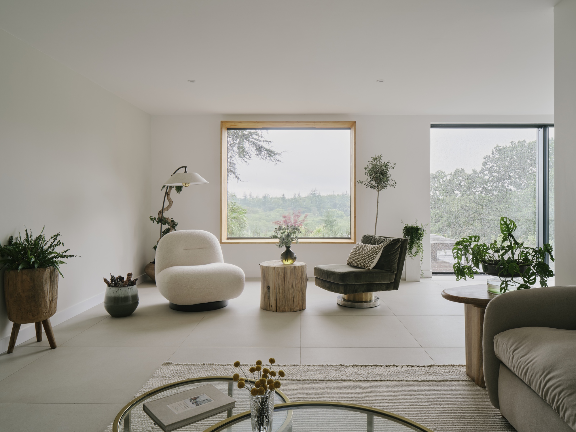 Living room with timber-framed window and corner glazing framing misty green landscape views