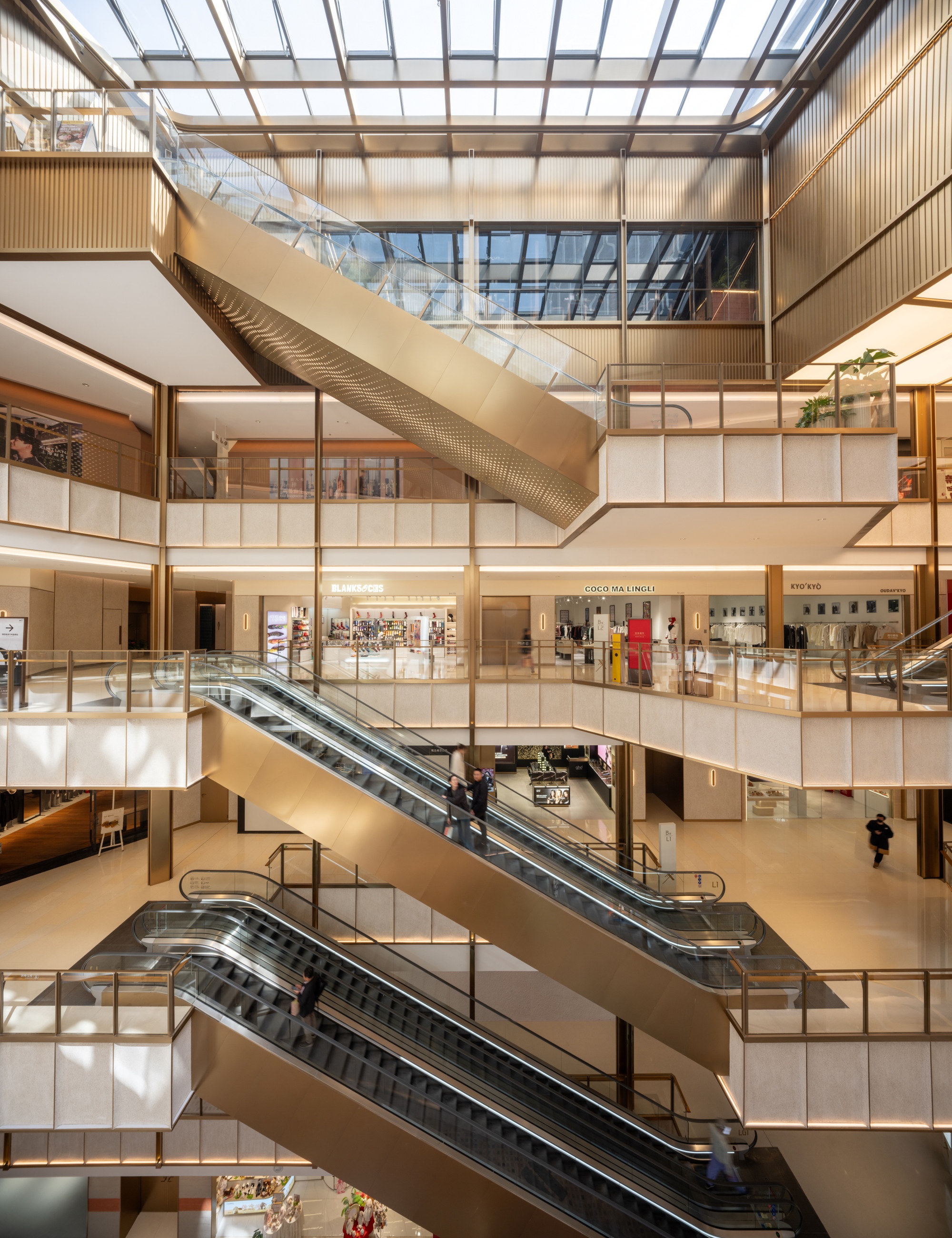 Multi-level atrium interior with escalators connecting floors beneath glazed roof and timber-clad balconies