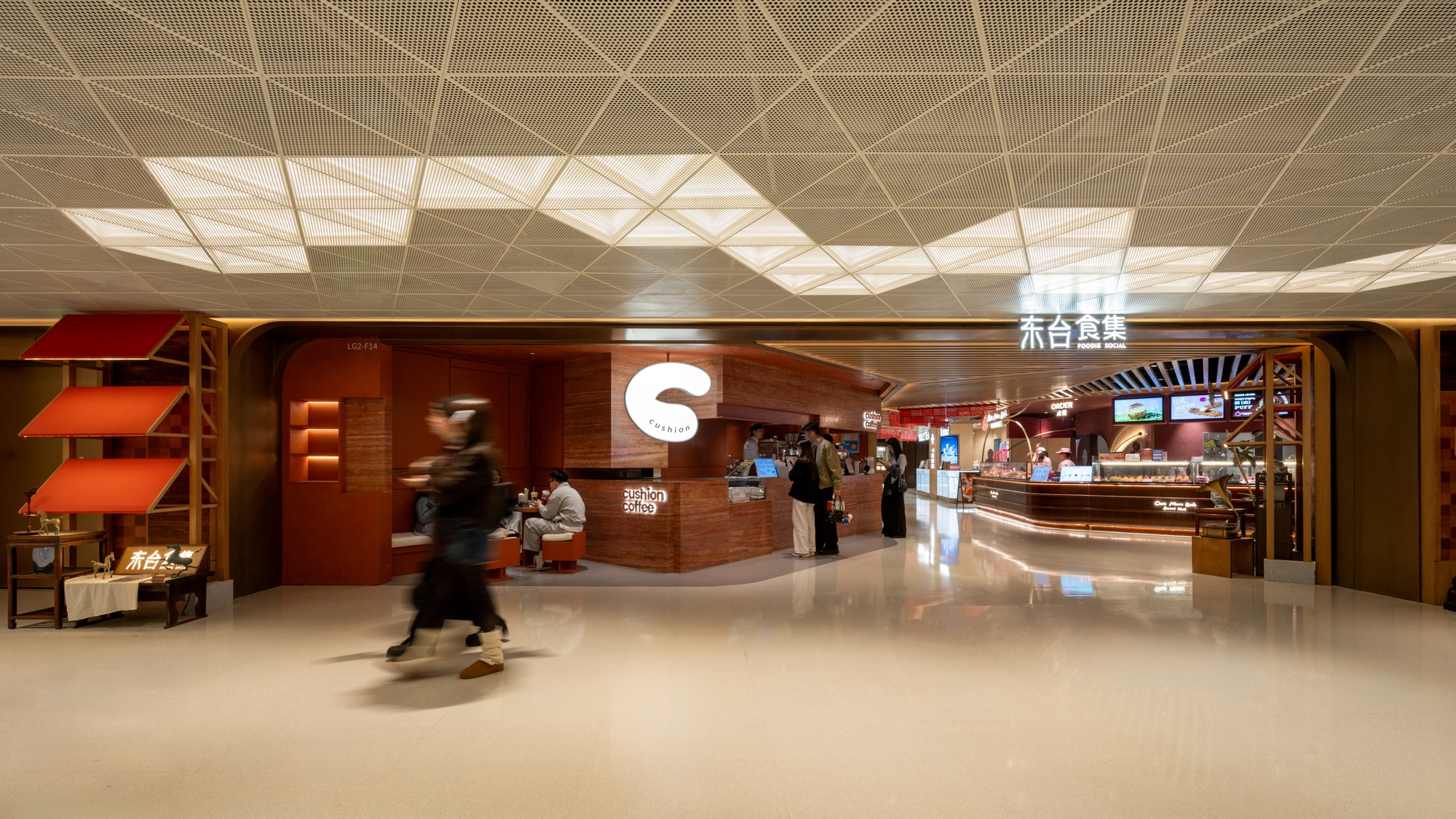 Food hall entrance with walnut cladding and geometric ceiling panel as a shopper passes by