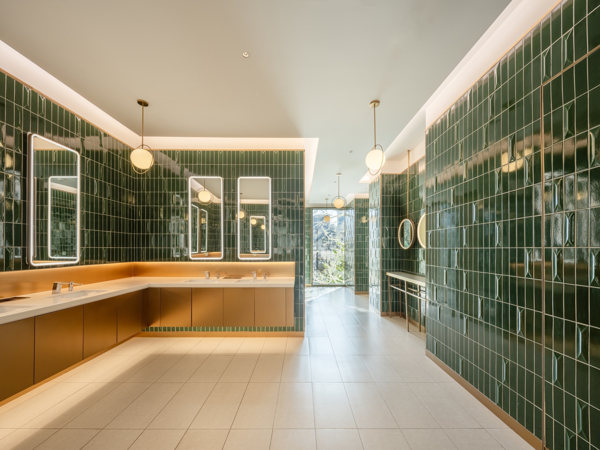 Restroom interior with green glazed tile walls and timber vanity under cove lighting