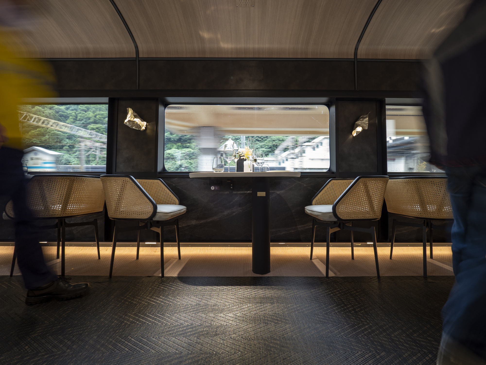 Train carriage dining booth with cane chairs and motion blur of passenger and passing landscape