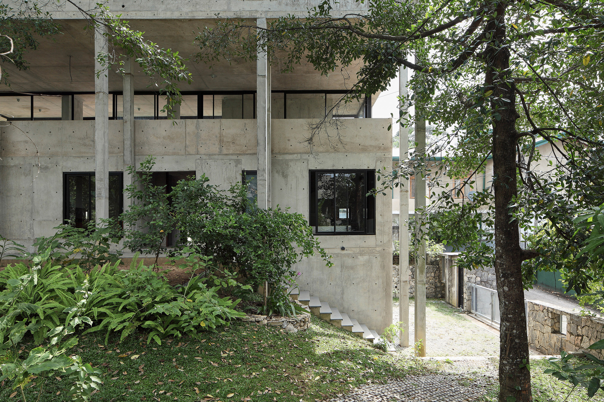 Angled view of the concrete volume with ribbon windows and landscaped hillside garden