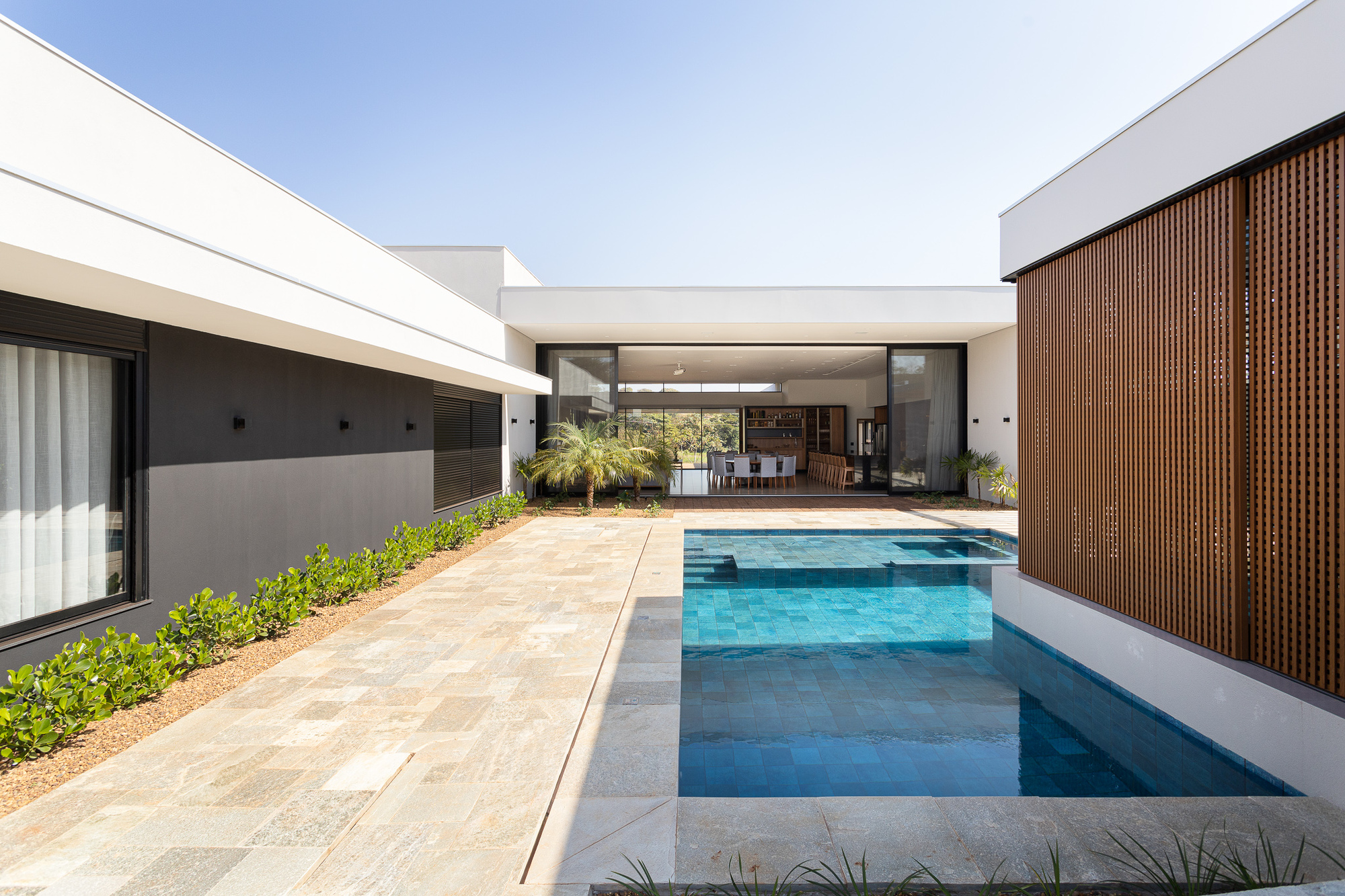 Courtyard pool with stone deck, vertical timber screen wall and shaded seating area beyond