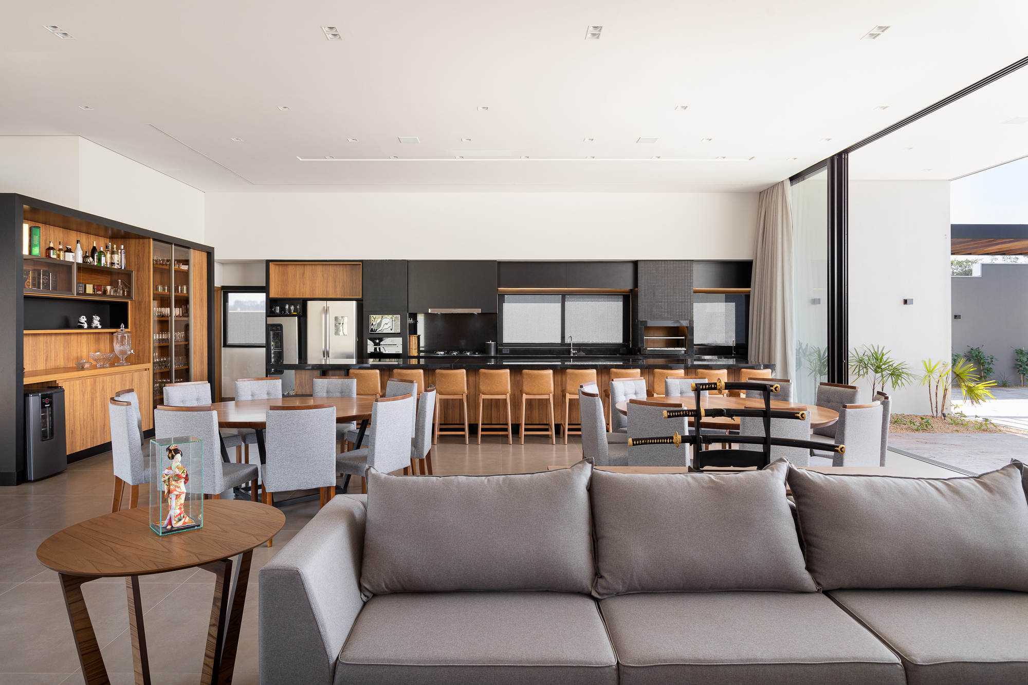 Open-plan living and dining area with timber cabinetry, grey upholstered seating, and sliding glass doors opening to a courtyard