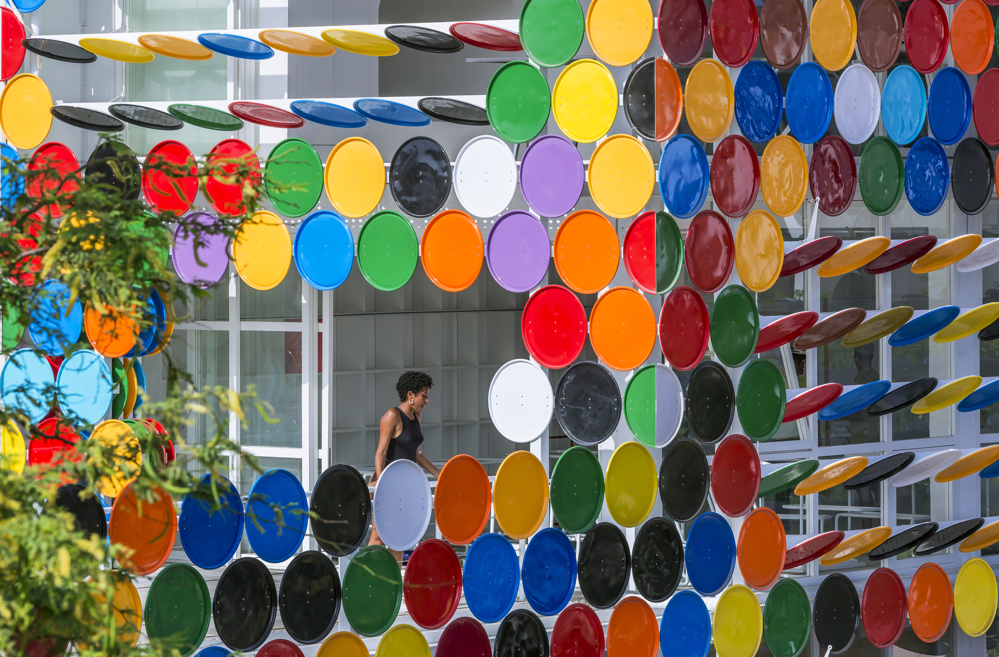 Interior view through the circular disc screen showing a figure walking past planted flowers in coloured pots