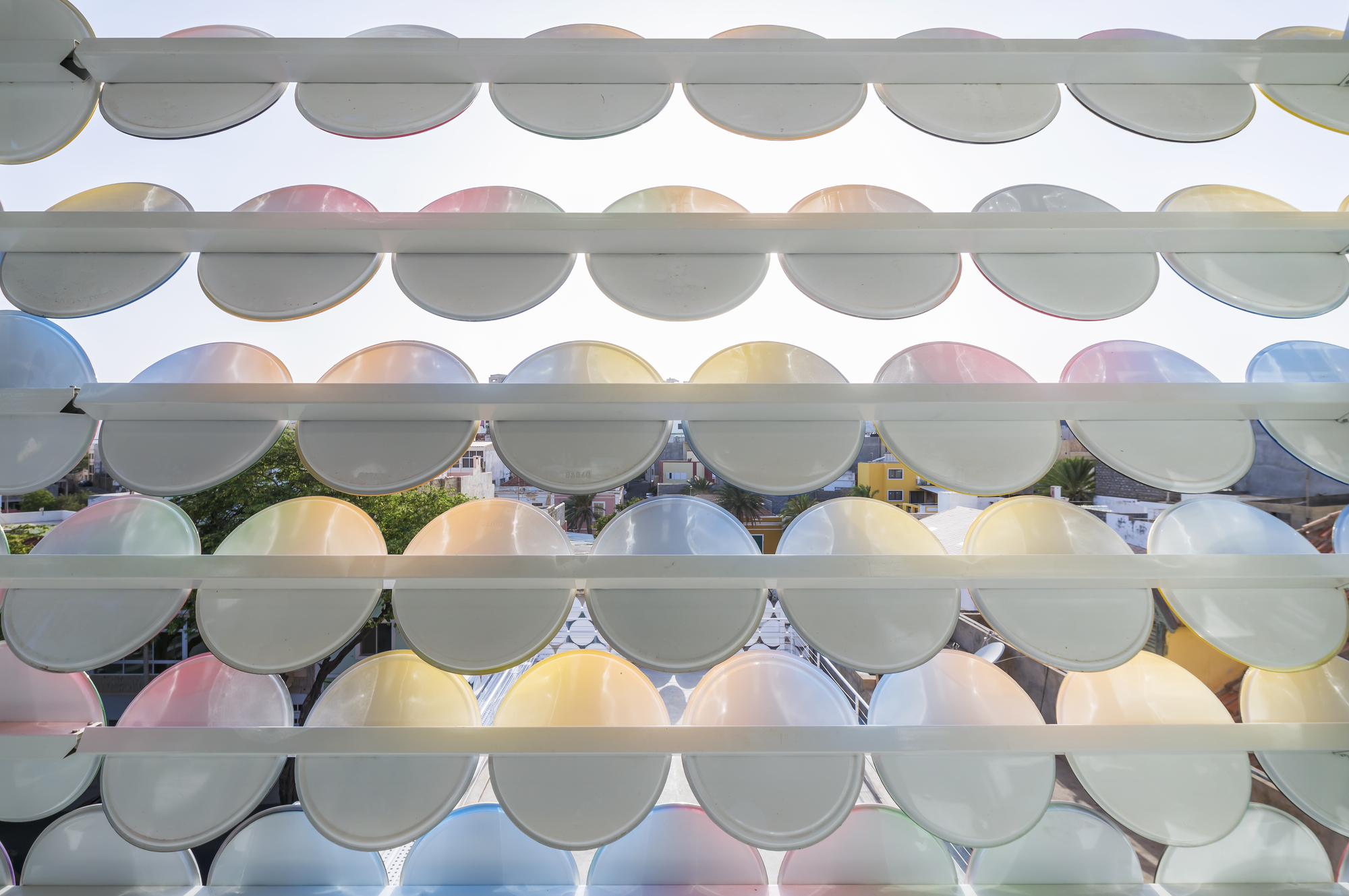 Facade detail showing overlapping translucent circular glass panels in pastel hues on horizontal supports