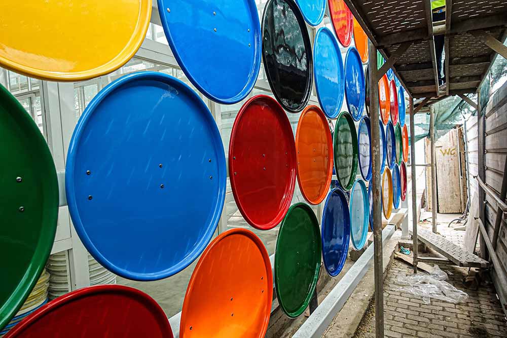 Interior view through circular colored glass panel wall with timber ceiling and construction debris beyond